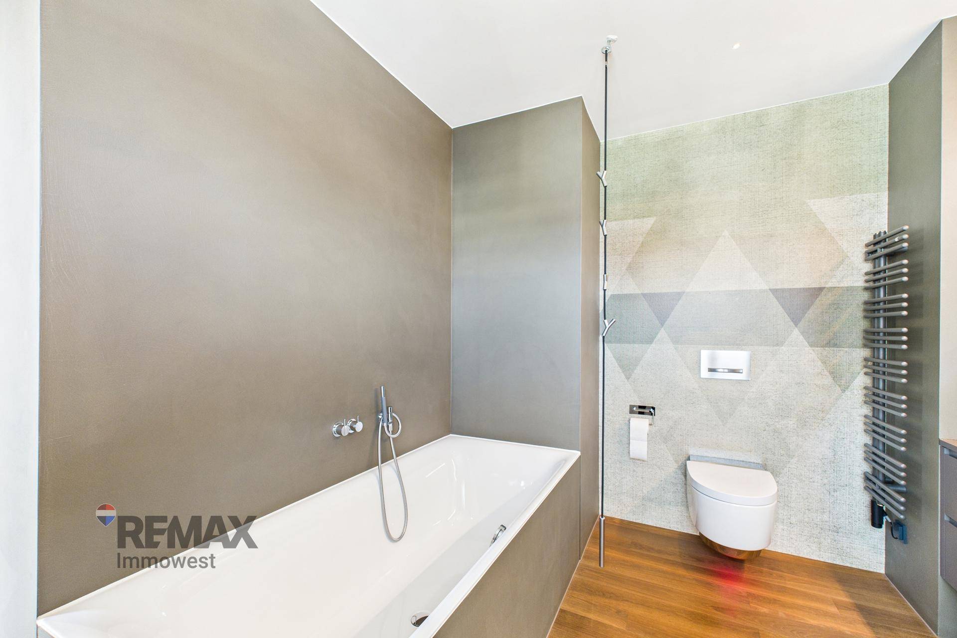 Modernes Badezimmer mit Badewanne, wandhängender Toilette und beheiztem Handtuchhalter.