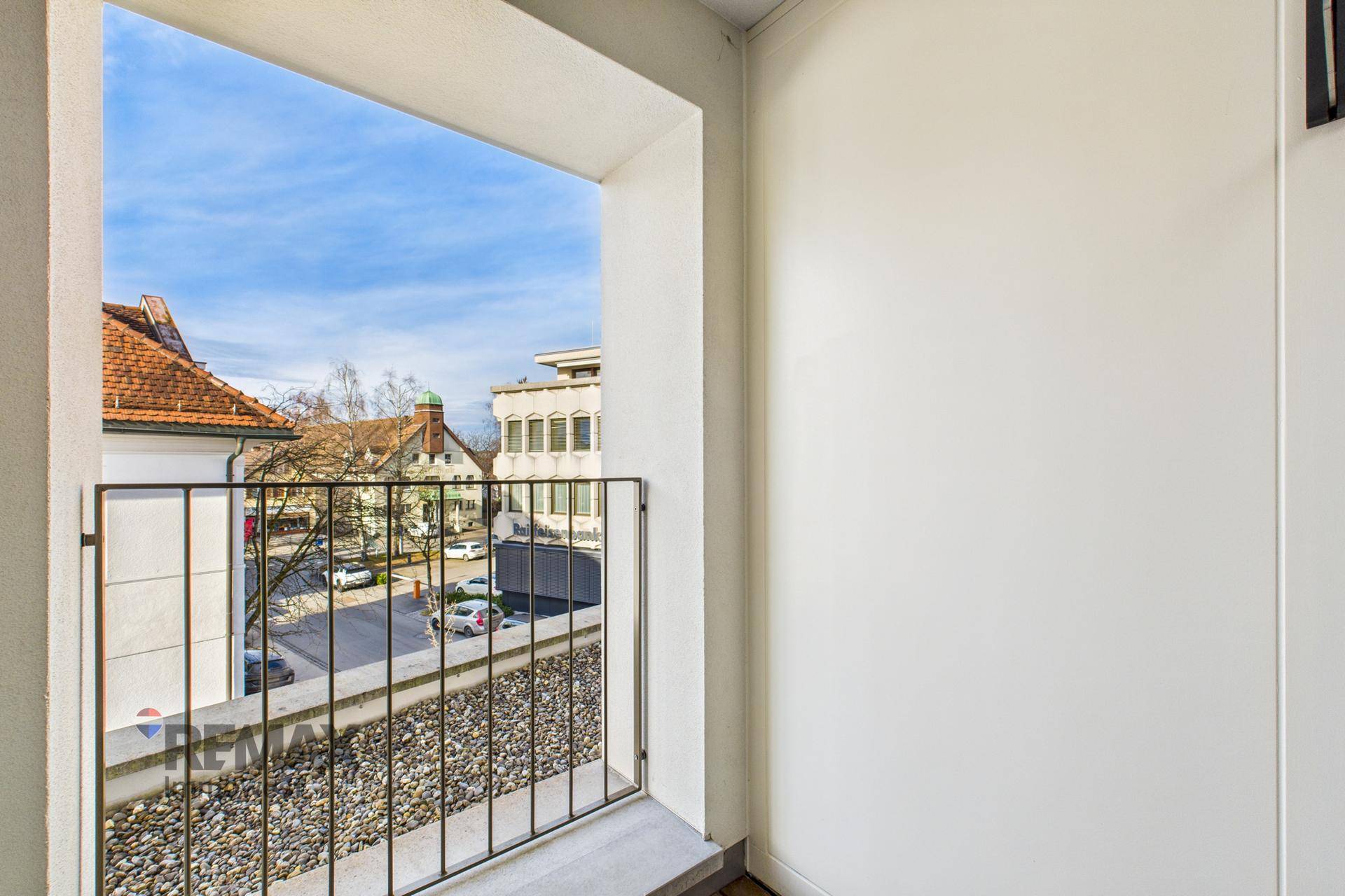 Französischer Balkon mit Metallgeländer und Blick auf die Straße und umliegende Gebäude.