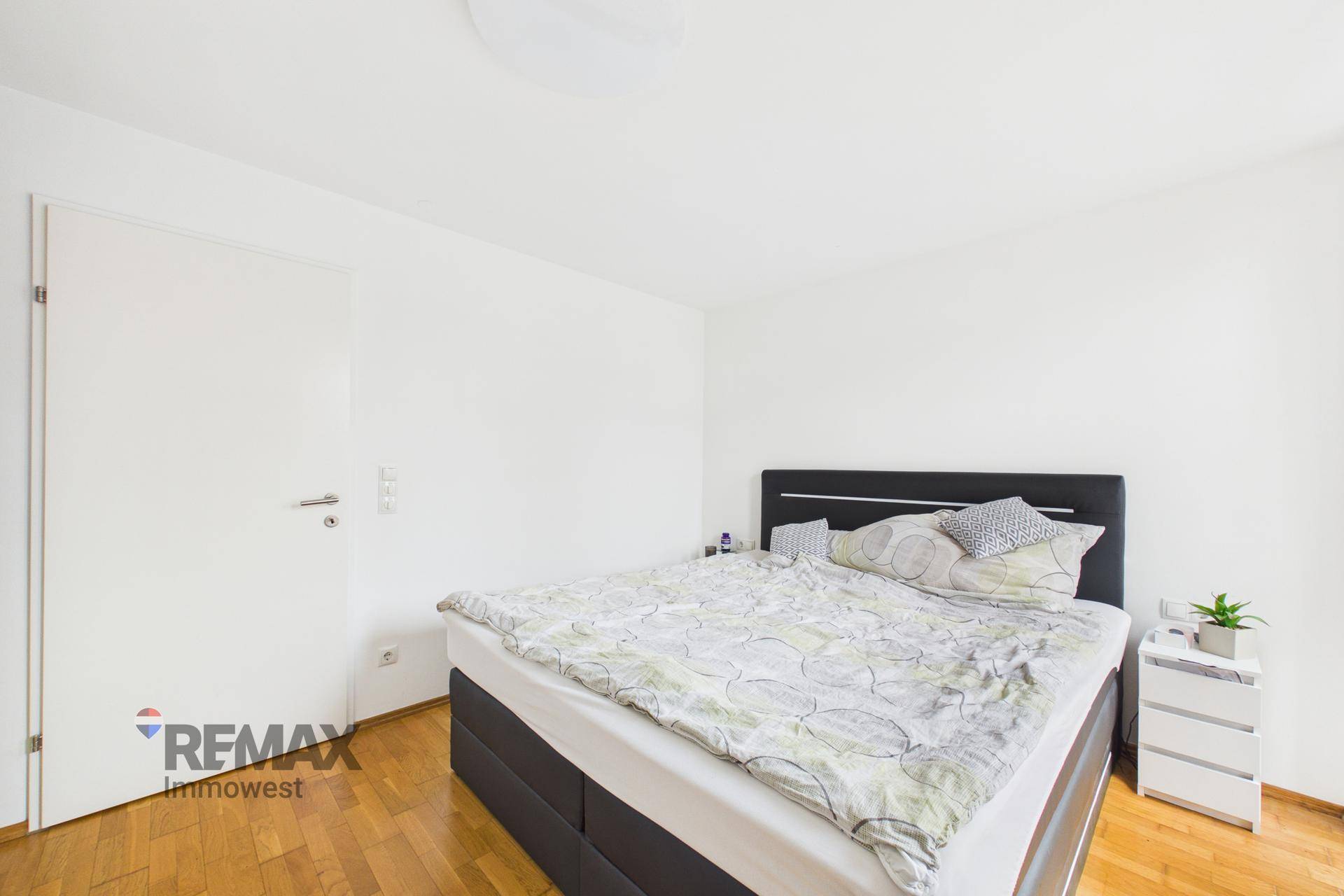 Geräumiges Schlafzimmer mit Holzboden und weiß gestrichenen Wänden, hell und einladend.