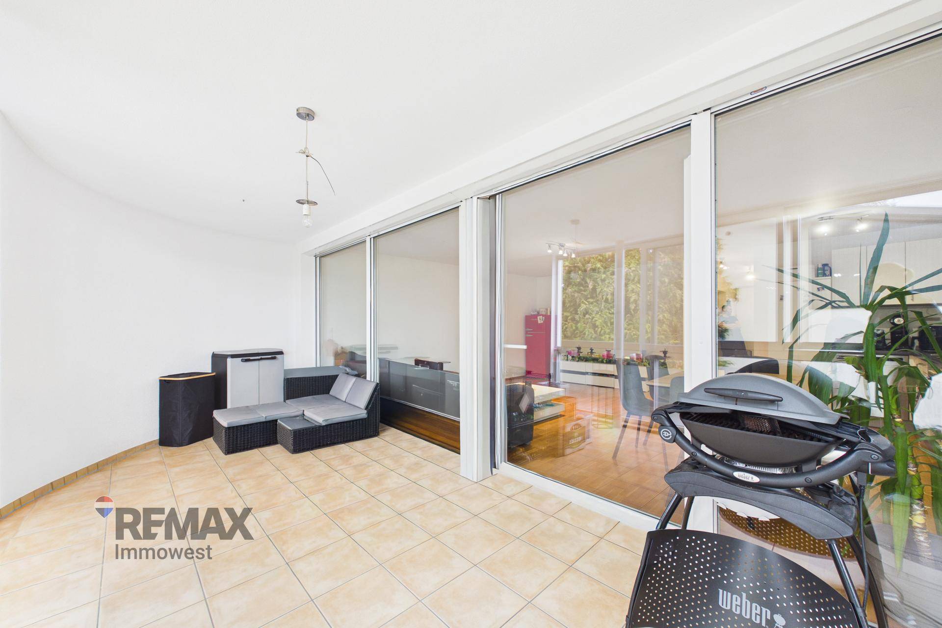 Geräumige Terrasse mit Fliesenboden und Grillbereich, ideal für entspannte Stunden im Freien.