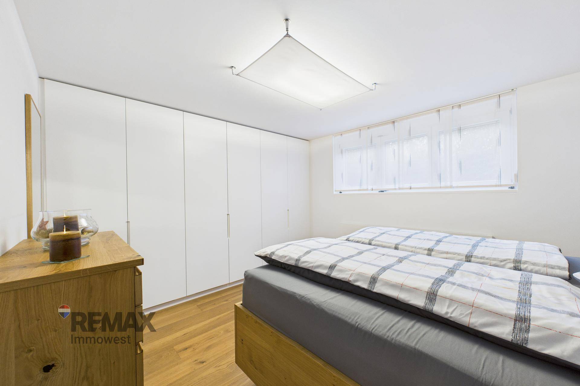 Schlafzimmer mit großem Holzbett, Einbauschränken und Fenster für Helligkeit.