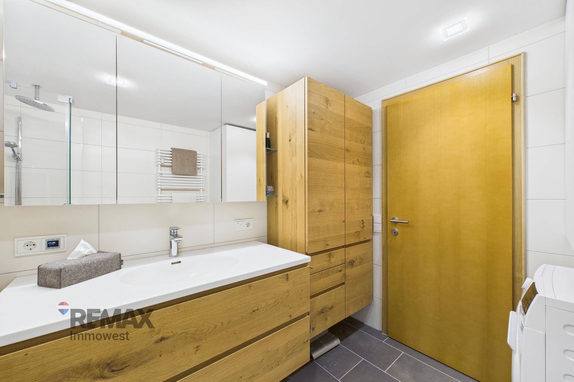 Modernes Badezimmer mit Holzwaschtisch, Spiegelschrank und integrierter Dusche.