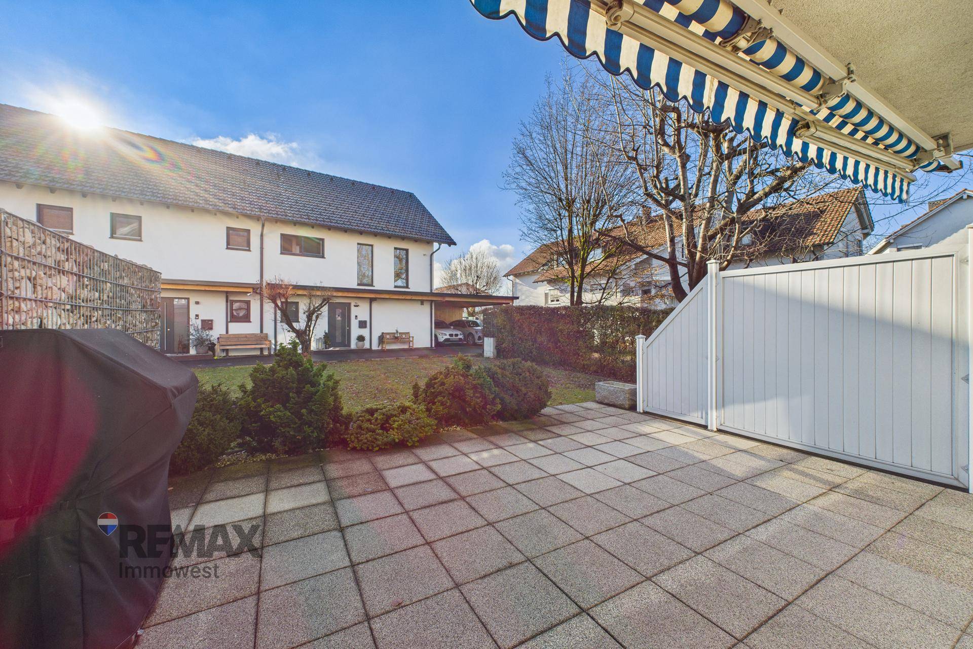 Große Terrasse mit Grillbereich und Blick auf den gepflegten Garten und das Gebäude.