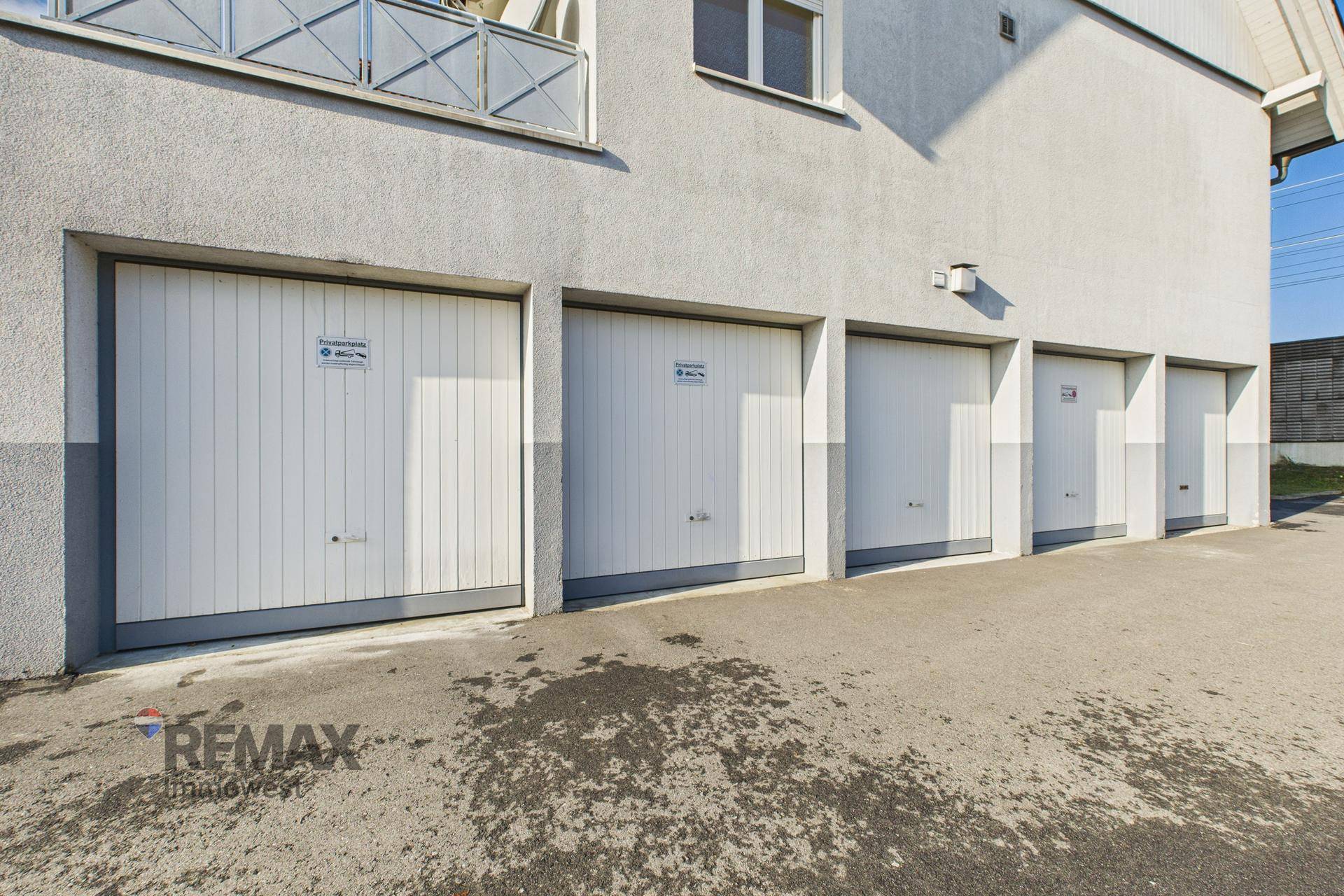 Reihe von Garagen mit weißen Toren und direktem Zugang zum Gebäude.