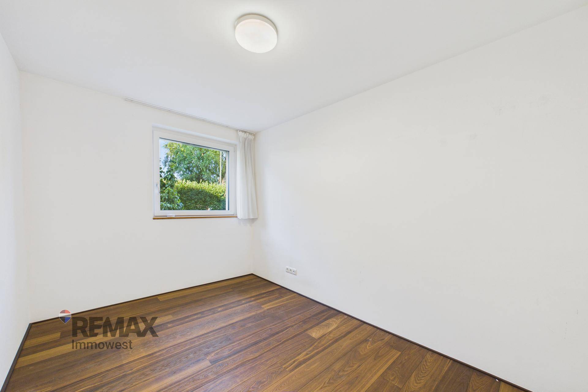 Heller Raum mit Holzboden und einem Fenster, ideal als Schlaf- oder Arbeitszimmer.