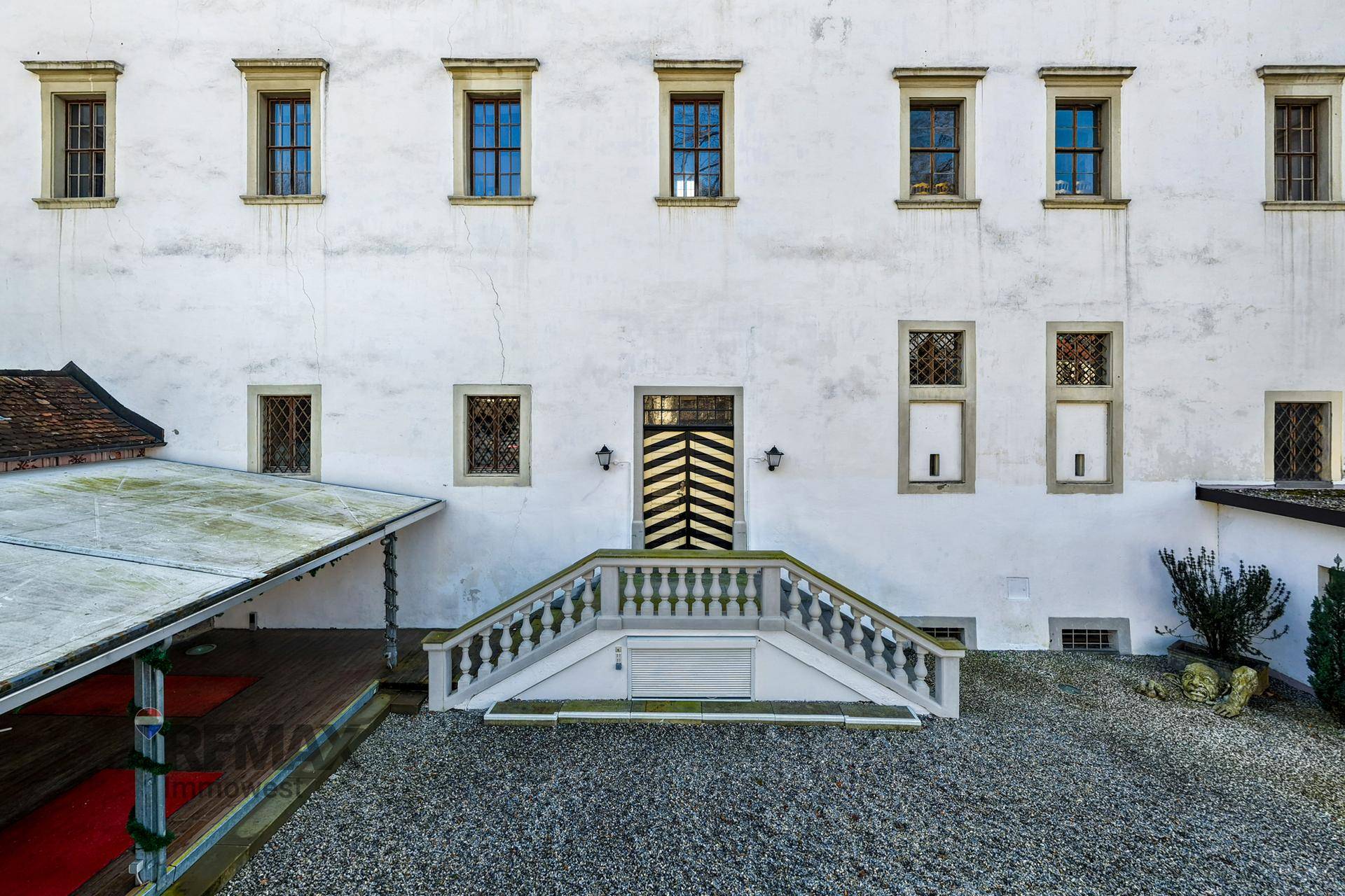Detailansicht der historischen Fassade mit markantem Eingang und vielen Fenstern.