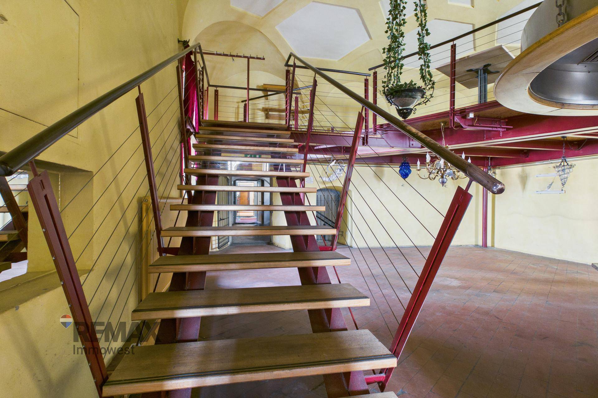 Treppe mit Metallgeländer führt zu einer oberen Ebene in einem großen Raum.