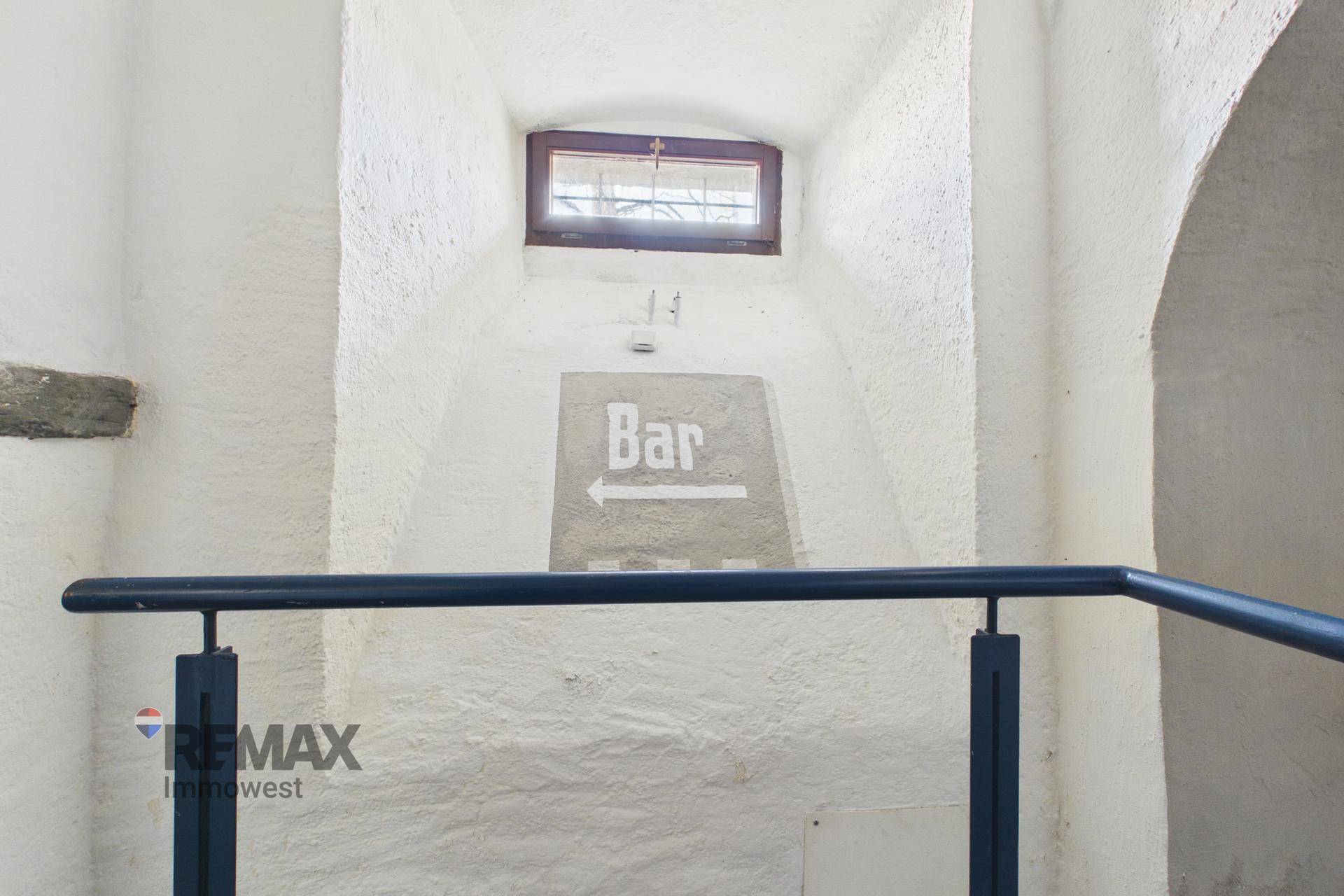 Detailansicht eines Fensters und eines Hinweisschildes "Bar" in einem gewölbten Treppenhaus.