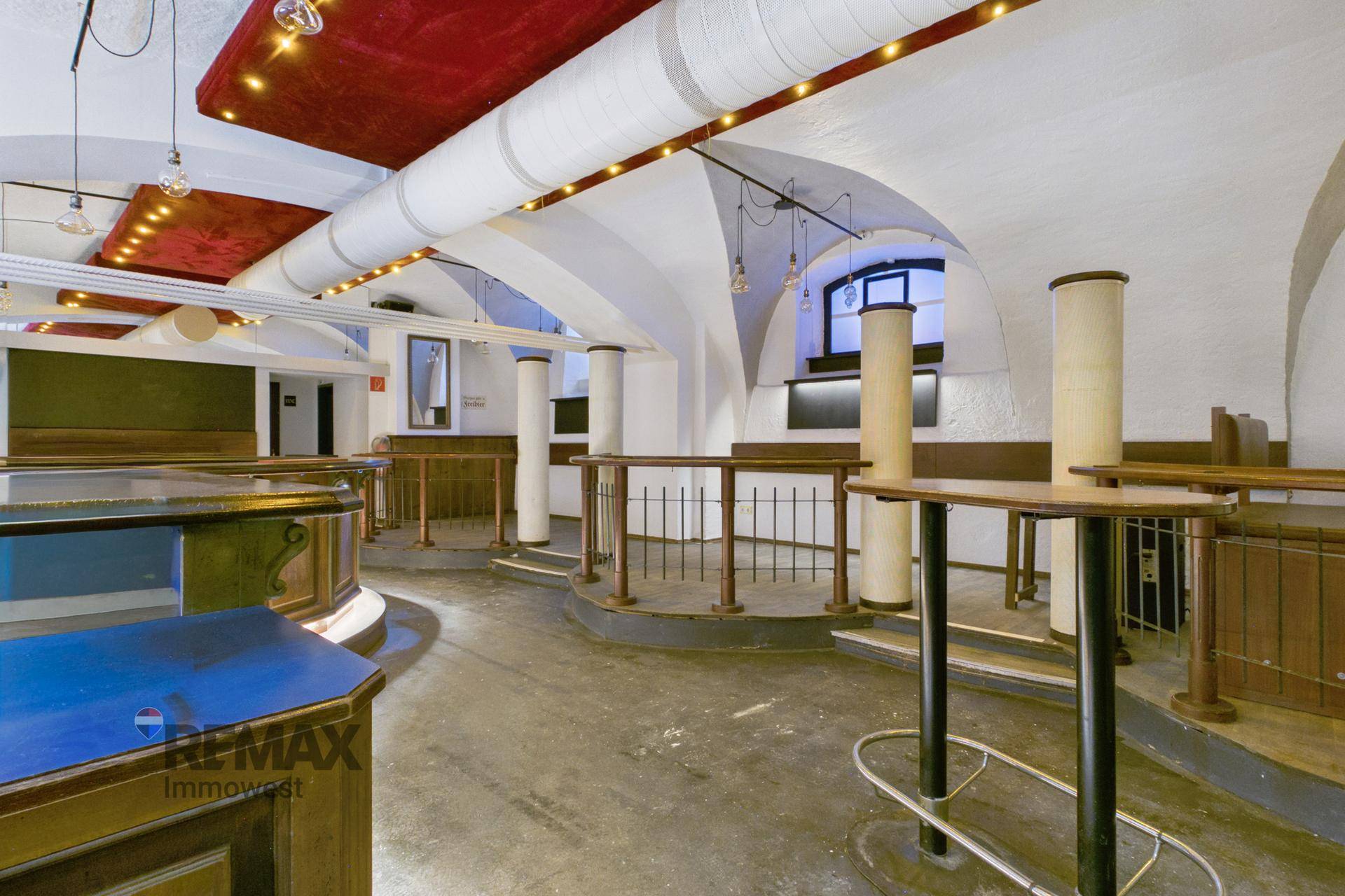 Sitzbereich in der Bar mit erhöhten Podesten, Geländern und gewölbter Decke.