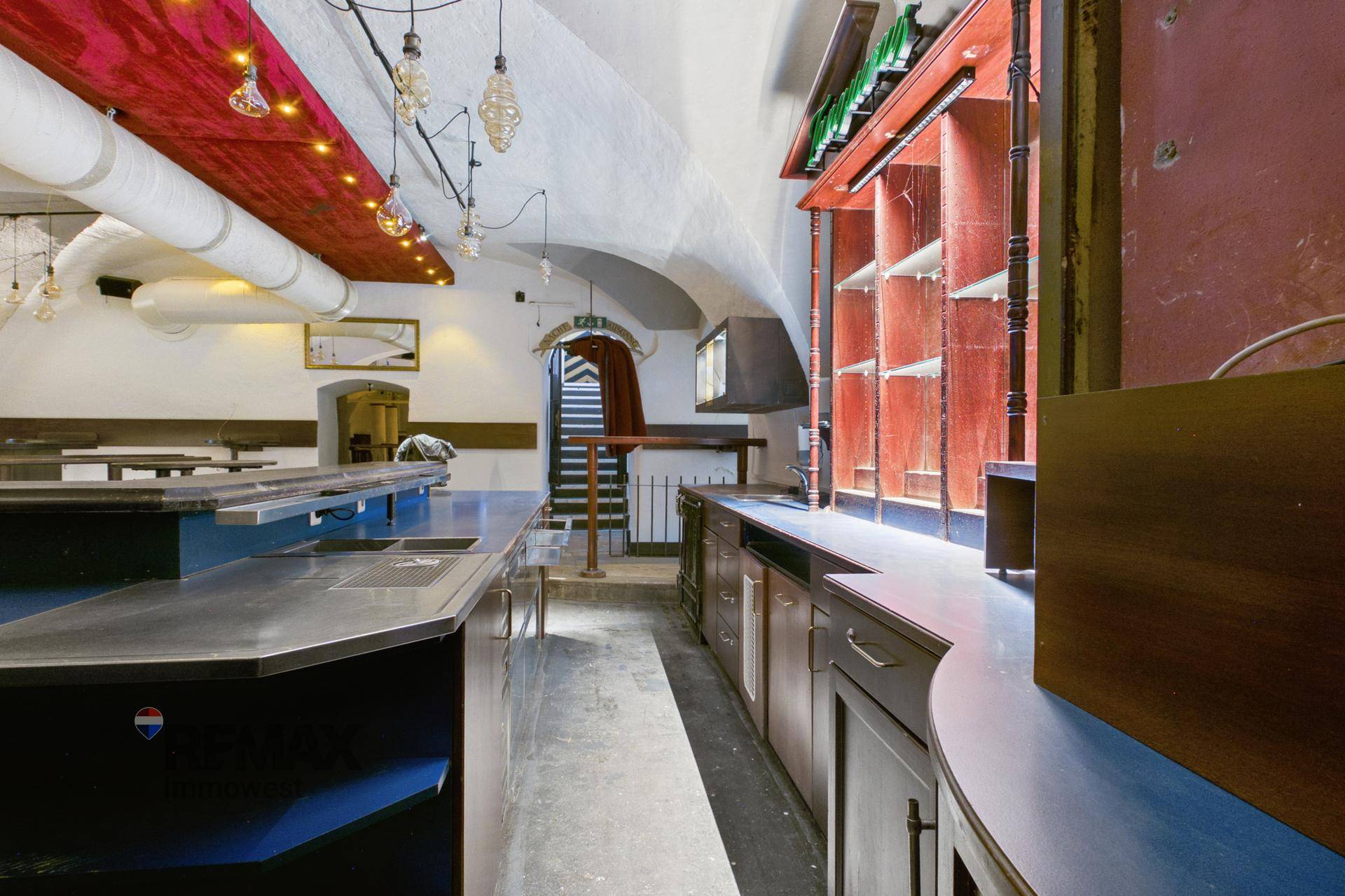 Bar-Bereich mit langen Theken, gewölbter Decke und sichtbaren Lüftungsrohren.