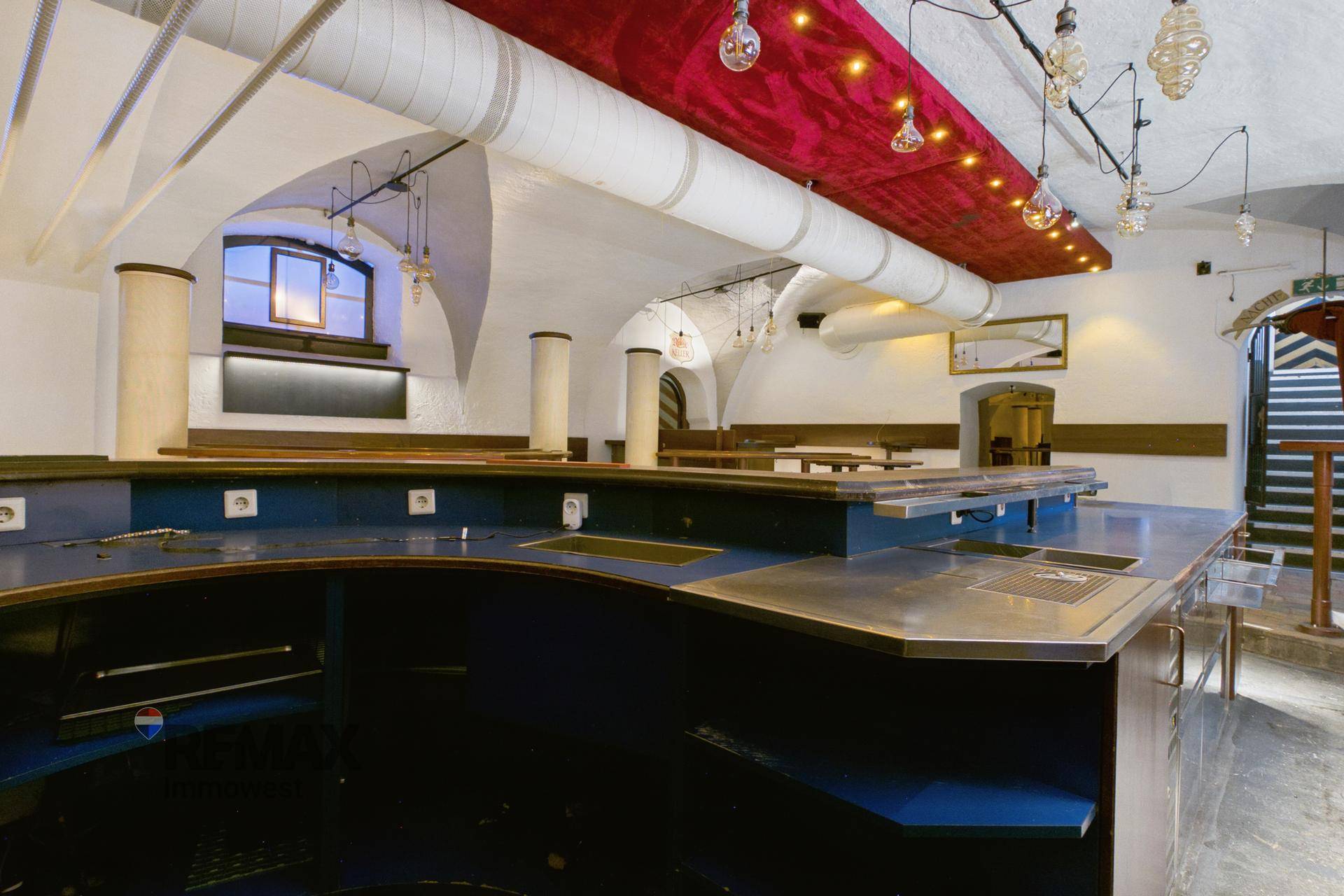 Geräumiger Bar-Bereich mit blauen Theken, gewölbter Decke und indirekter Beleuchtung.