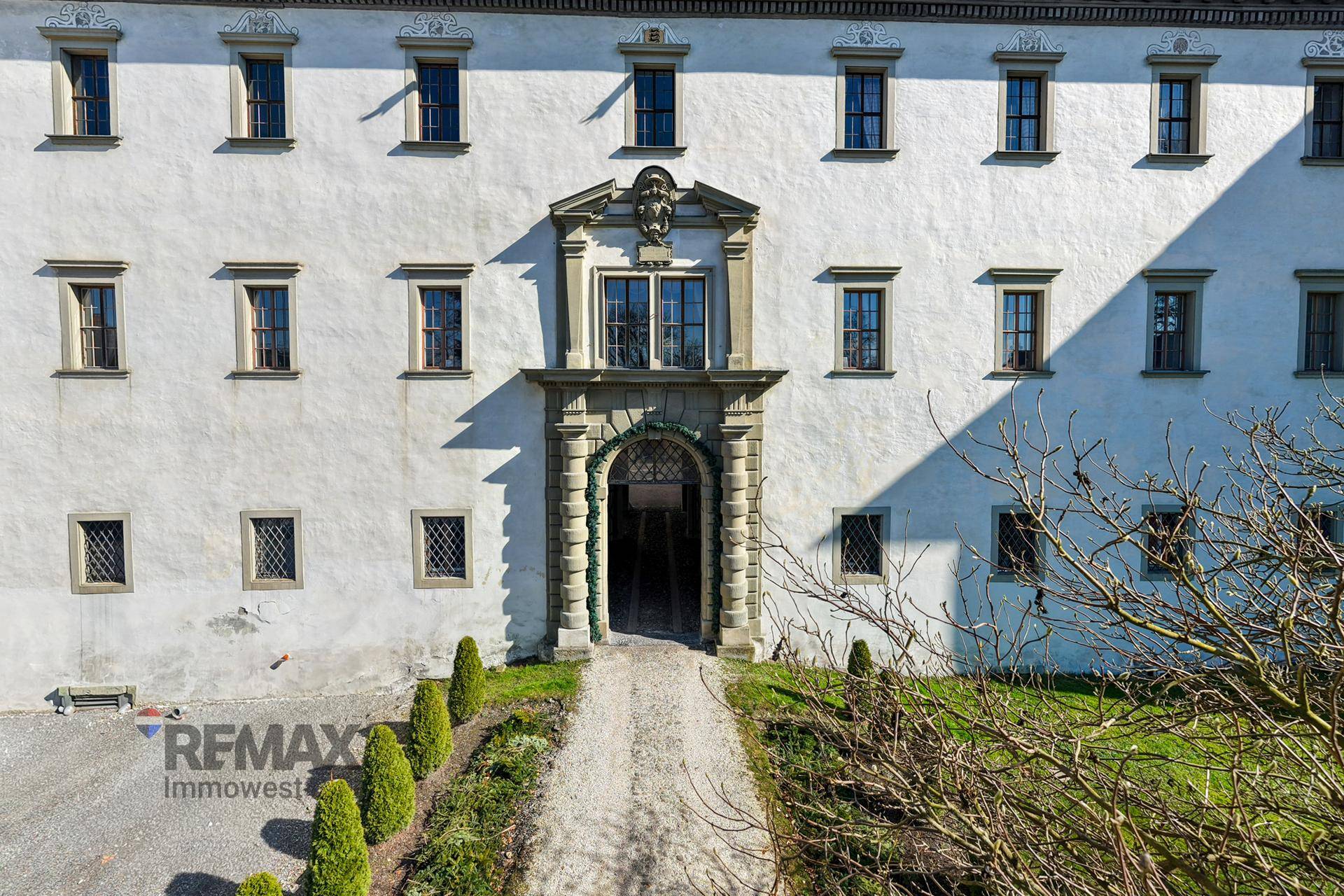 Prunkvolle Hauptfassade eines historischen Gebäudes mit aufwendigem Eingangsbereich und gepflegter Grünfläche.