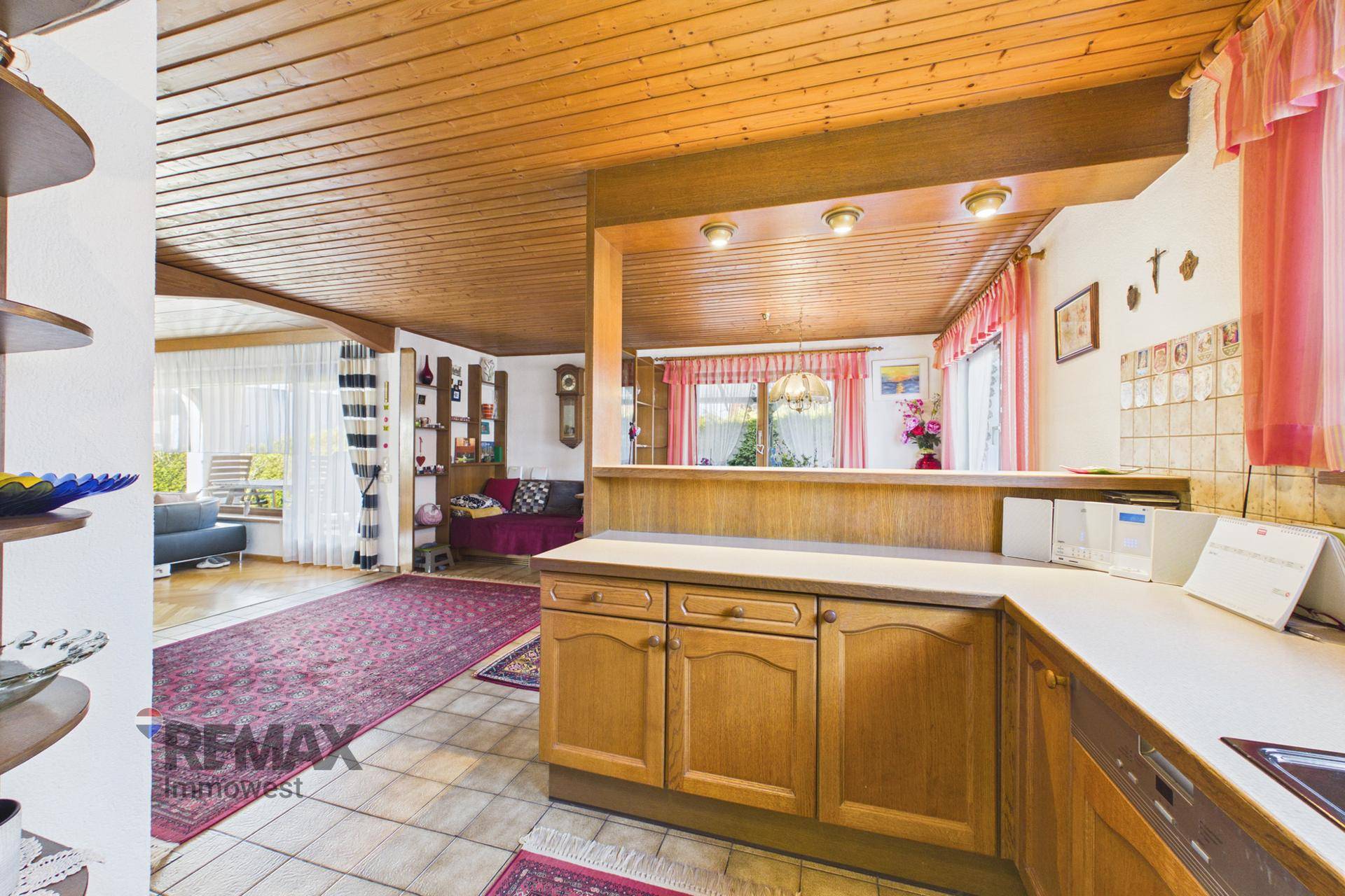 Halboffene Küche mit Holzschränken und Übergang zum Wohnbereich, ideal für geselliges Kochen.