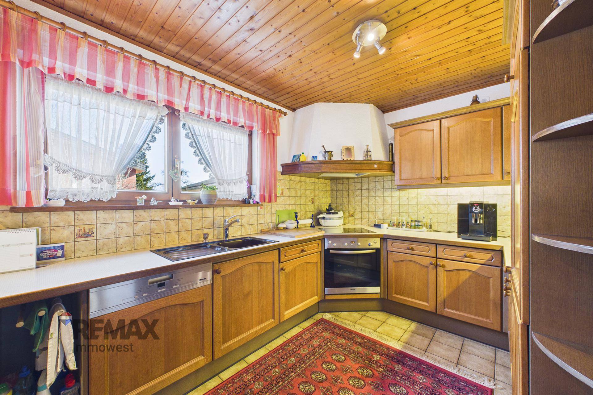 Traditionelle Holzküche mit Fliesenboden, Einbaugeräten und Fensterblick, gut gepflegt und funktional.
