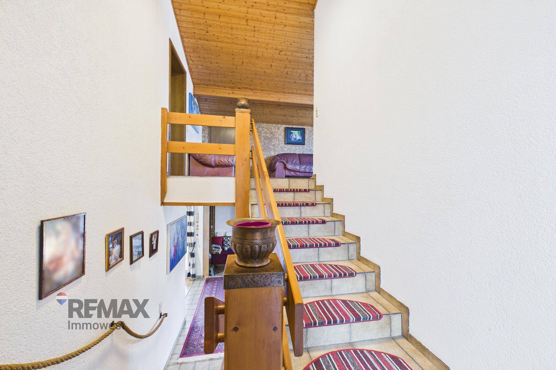 Treppenhaus mit Holzgeländer, Teppichläufern und Holzdecke, verbindet die Wohnebenen des Hauses.