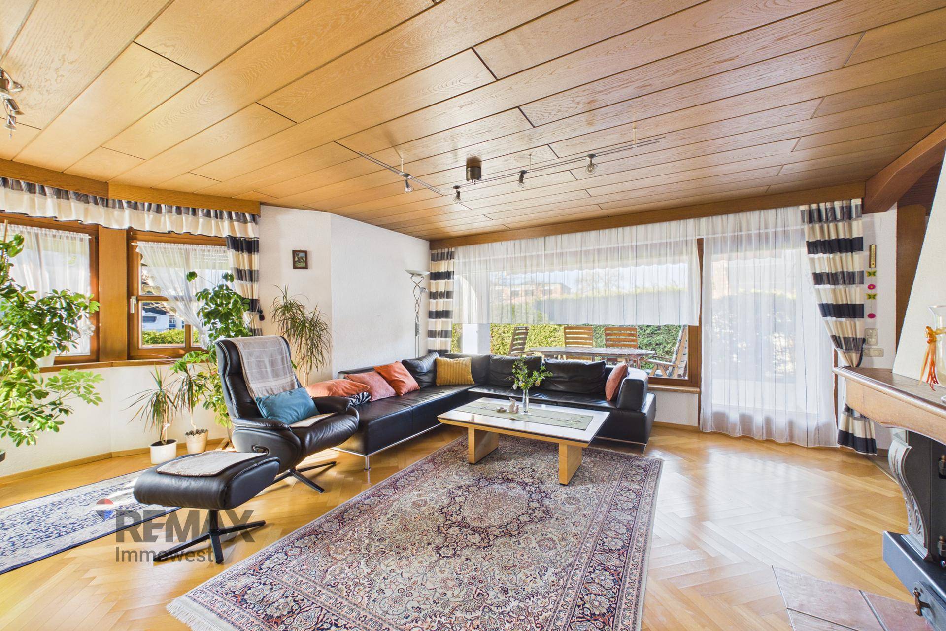 Geräumiges Wohnzimmer mit Parkettboden, Holzdecke und großen Fenstern zum Garten, hell und einladend.