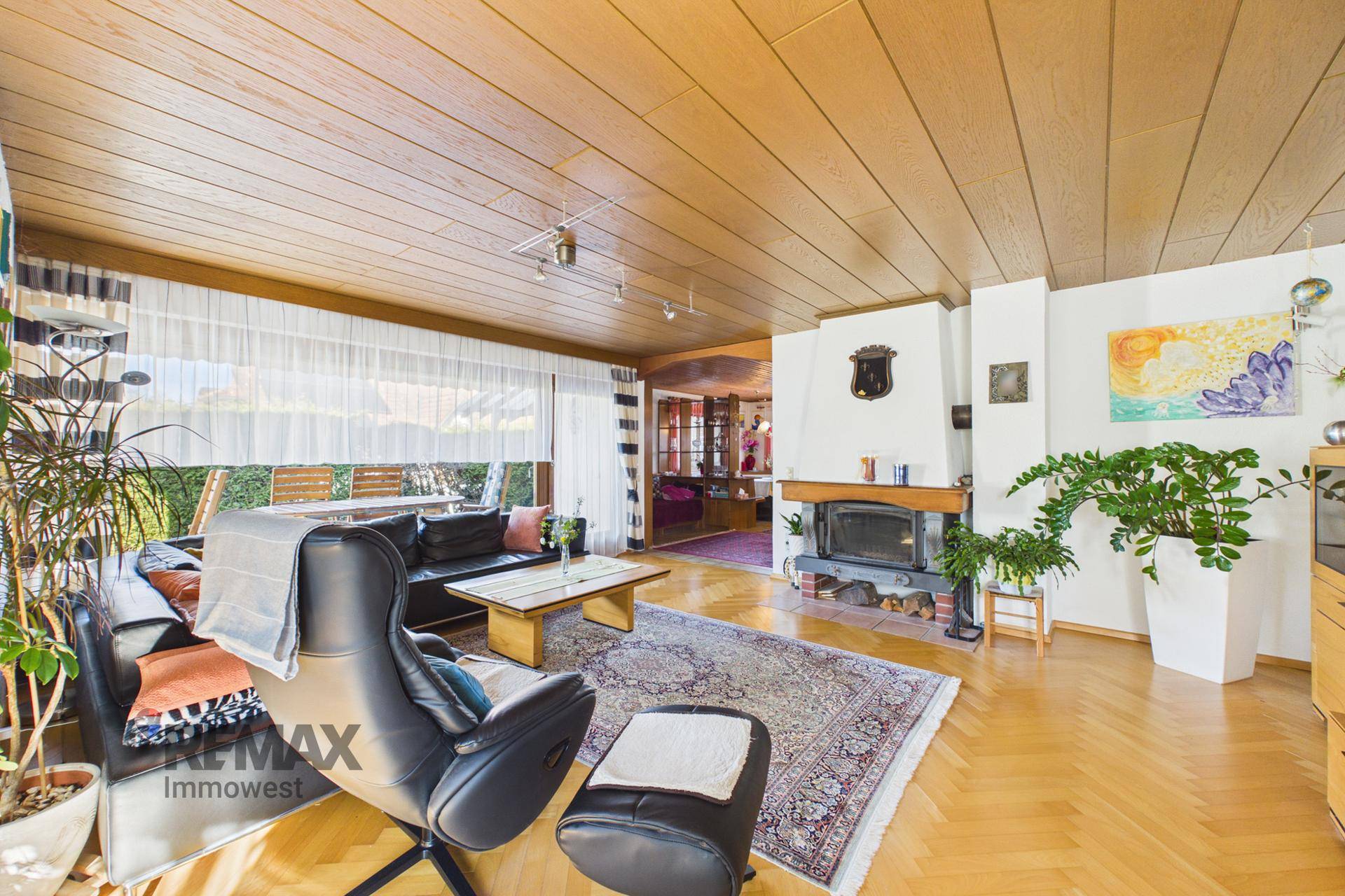Helles Wohnzimmer mit Kamin, Parkettboden und Zugang zum Außenbereich, perfekt für gemütliche Abende.