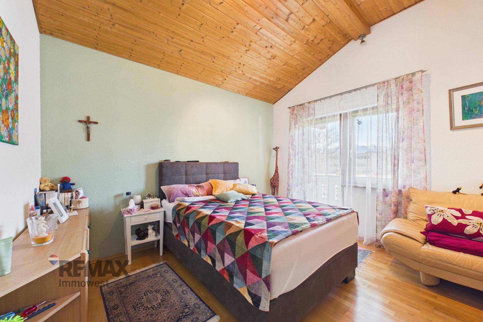 Schlafzimmer mit Holzdachschräge, Parkettboden und Bergblick, bietet eine ruhige und helle Atmosphäre.