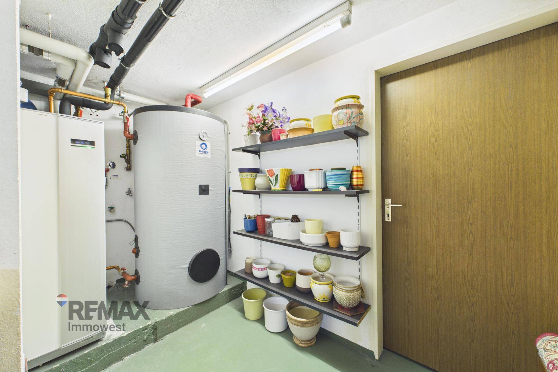 Heizungsraum mit Warmwasserspeicher und Regalen für Lagerung, funktional und gut organisiert.