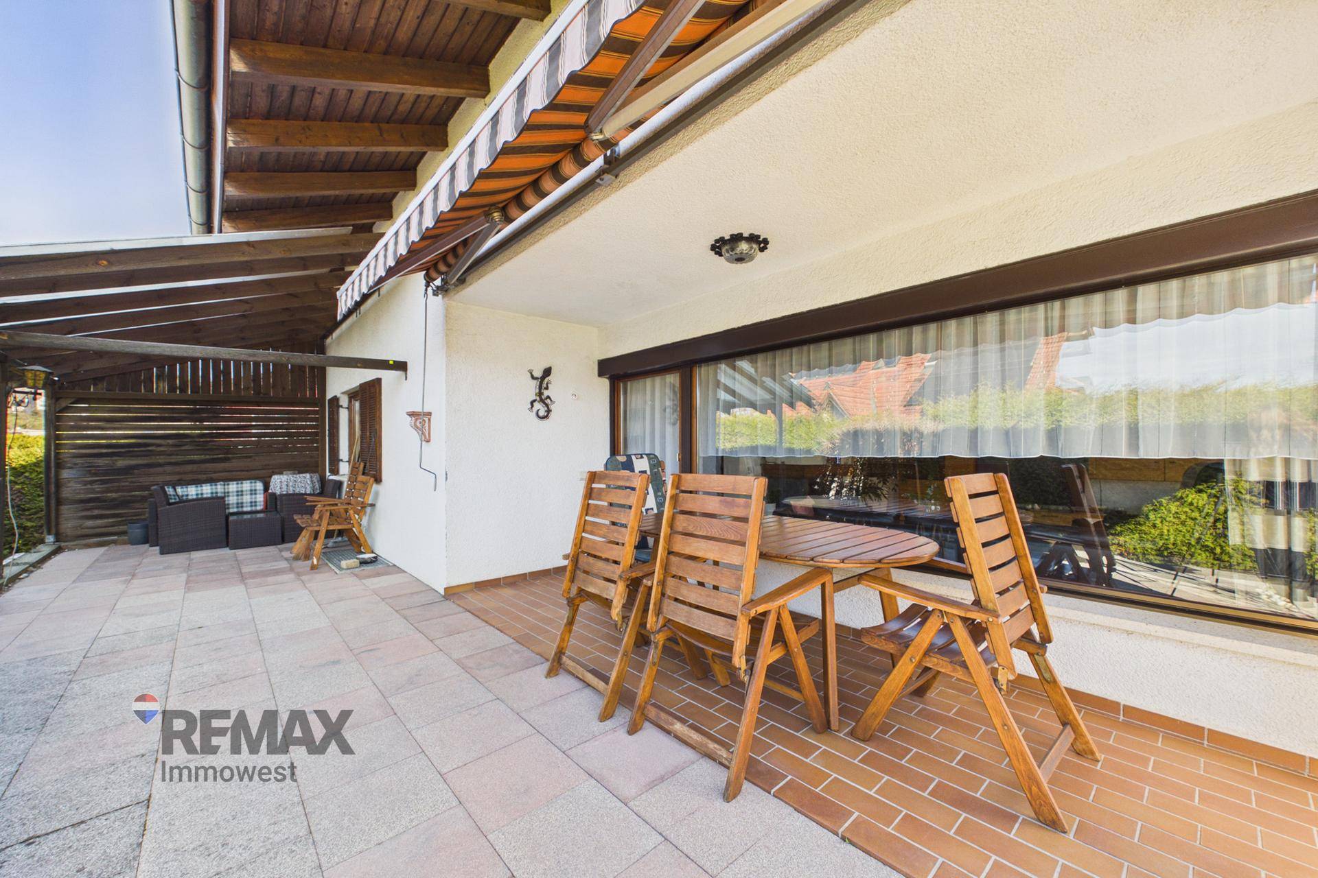 Überdachte Terrasse mit Gartenmöbeln und Markise, ideal für Mahlzeiten im Freien und Entspannung.