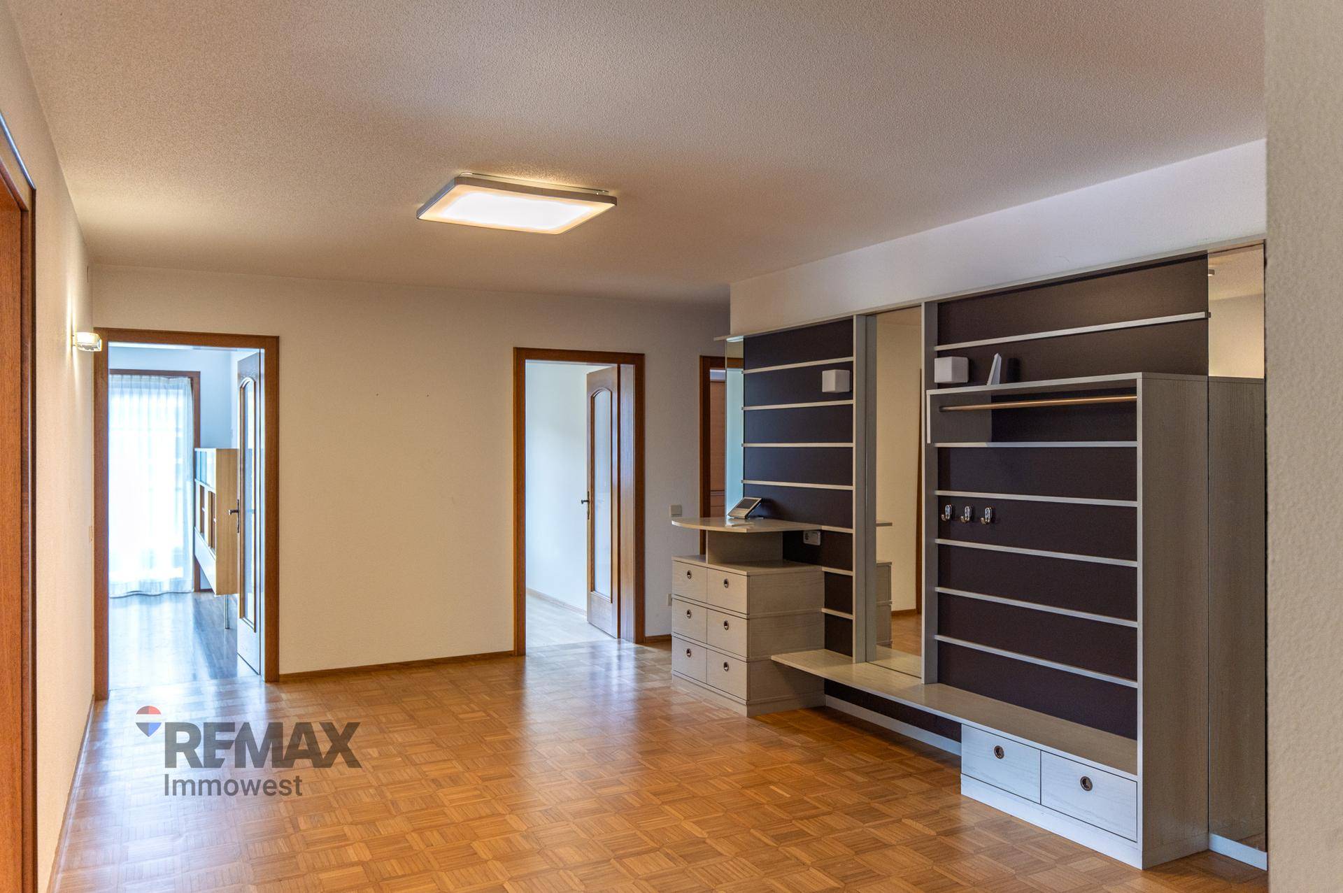 Geräumiger Flur mit Holzparkettboden und einem modernen Garderobenschrank mit Spiegel.