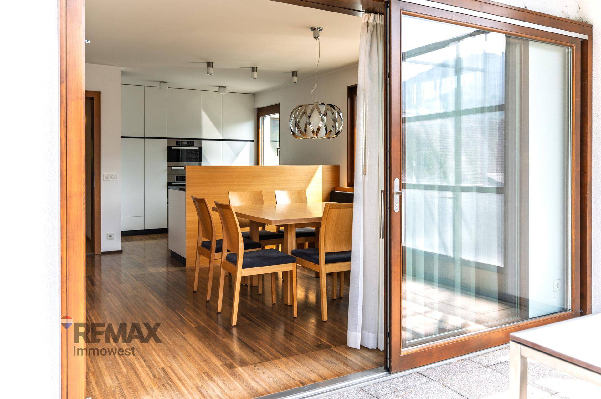 Heller Essbereich mit Holztisch und Zugang zu einem Balkon durch eine große Glasschiebetür.