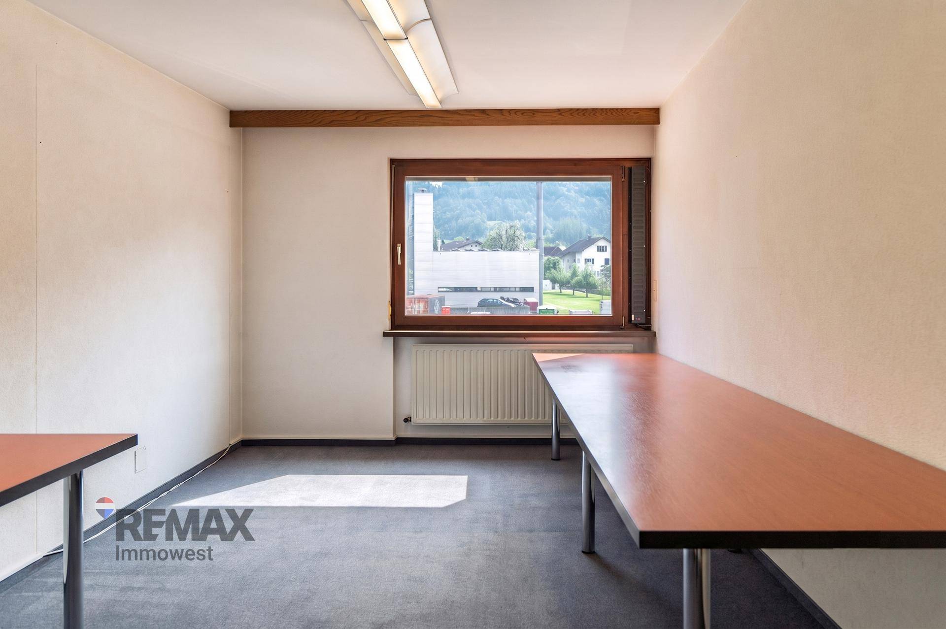 Geräumiges Büro mit Teppichboden und langen Arbeitstischen, ideal für mehrere Arbeitsplätze.