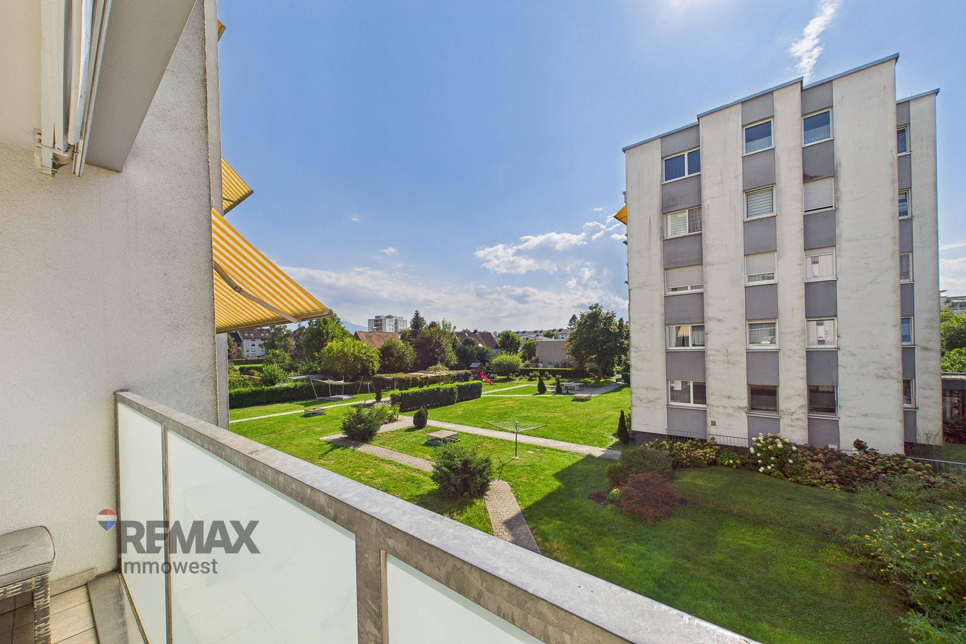 Balkon mit Blick auf die grüne Gemeinschaftsanlage und umliegende Wohngebäude.