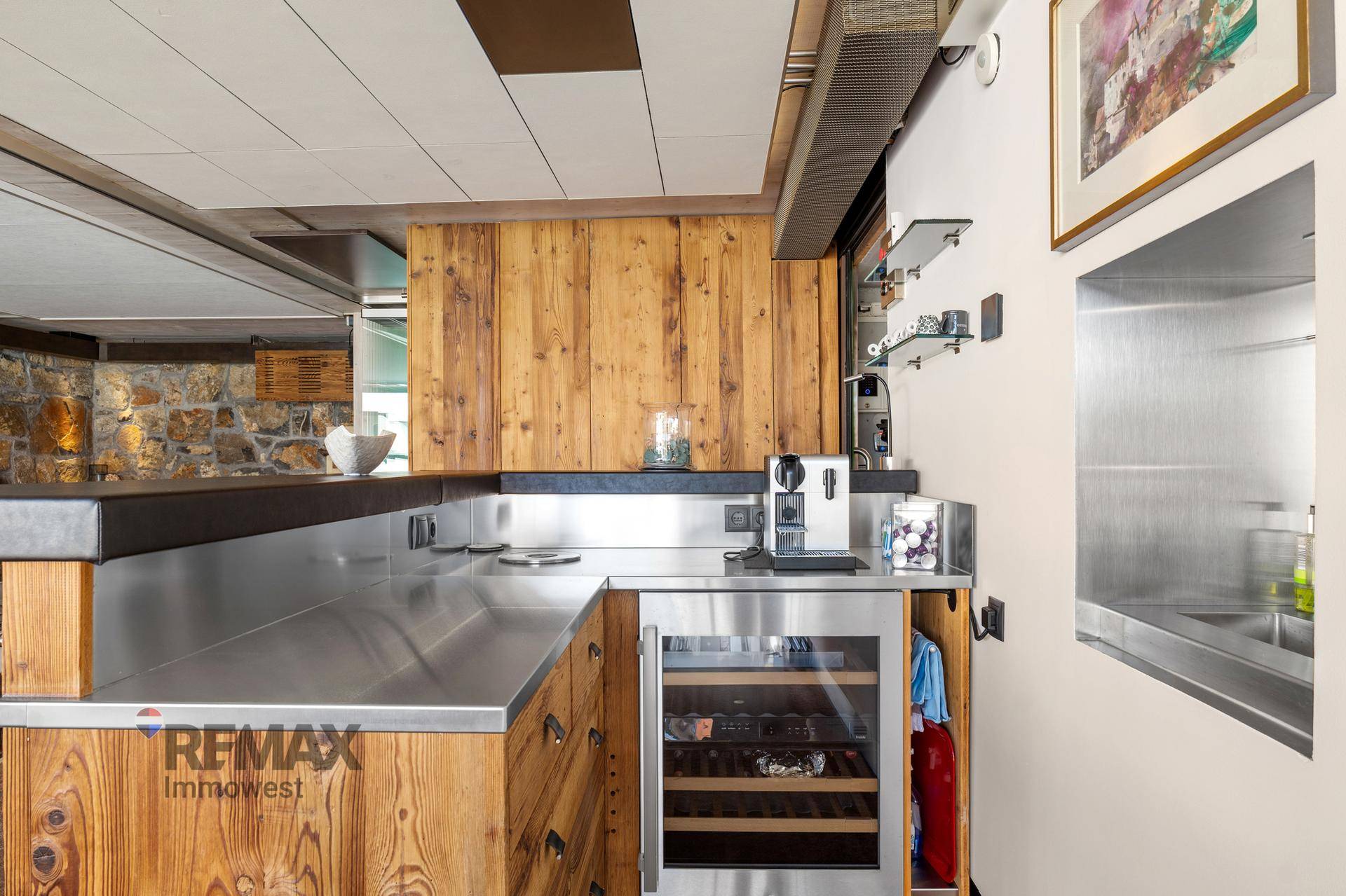 Moderne Holzküche mit Edelstahlarbeitsflächen und integriertem Weinkühlschrank.