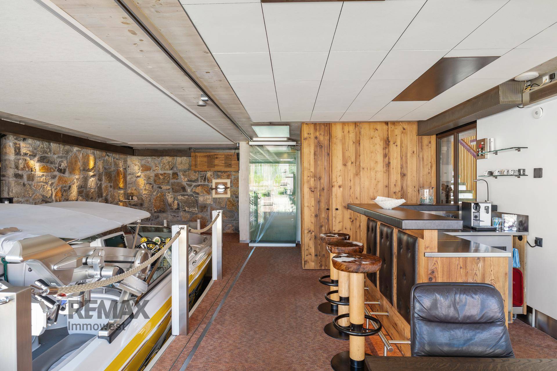 Gemütlicher Barbereich mit Holztheke und Hockern neben dem Bootsliegeplatz.