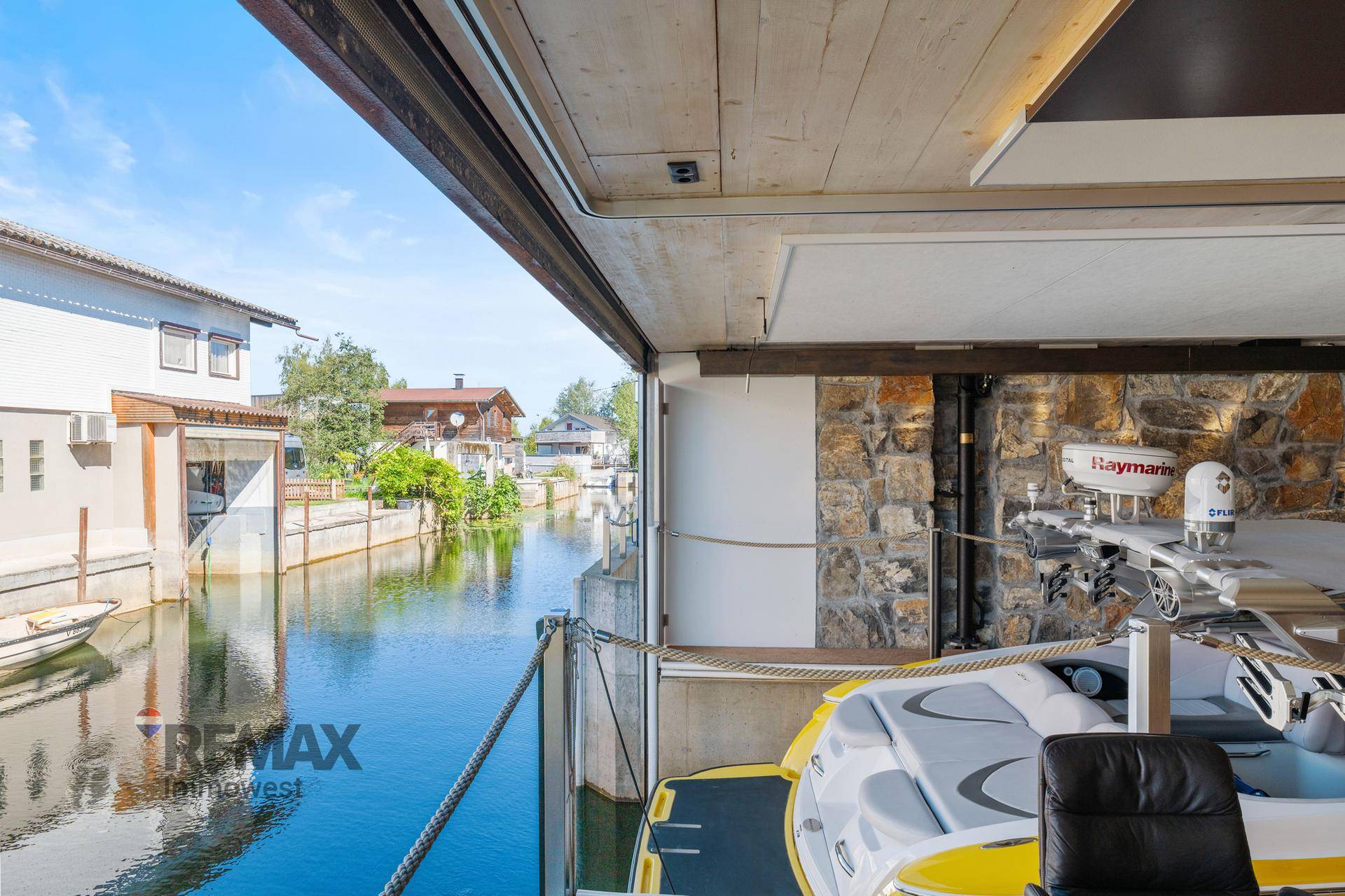 Blick aus dem Bootshaus auf den sonnigen Kanal und die umliegenden Häuser.