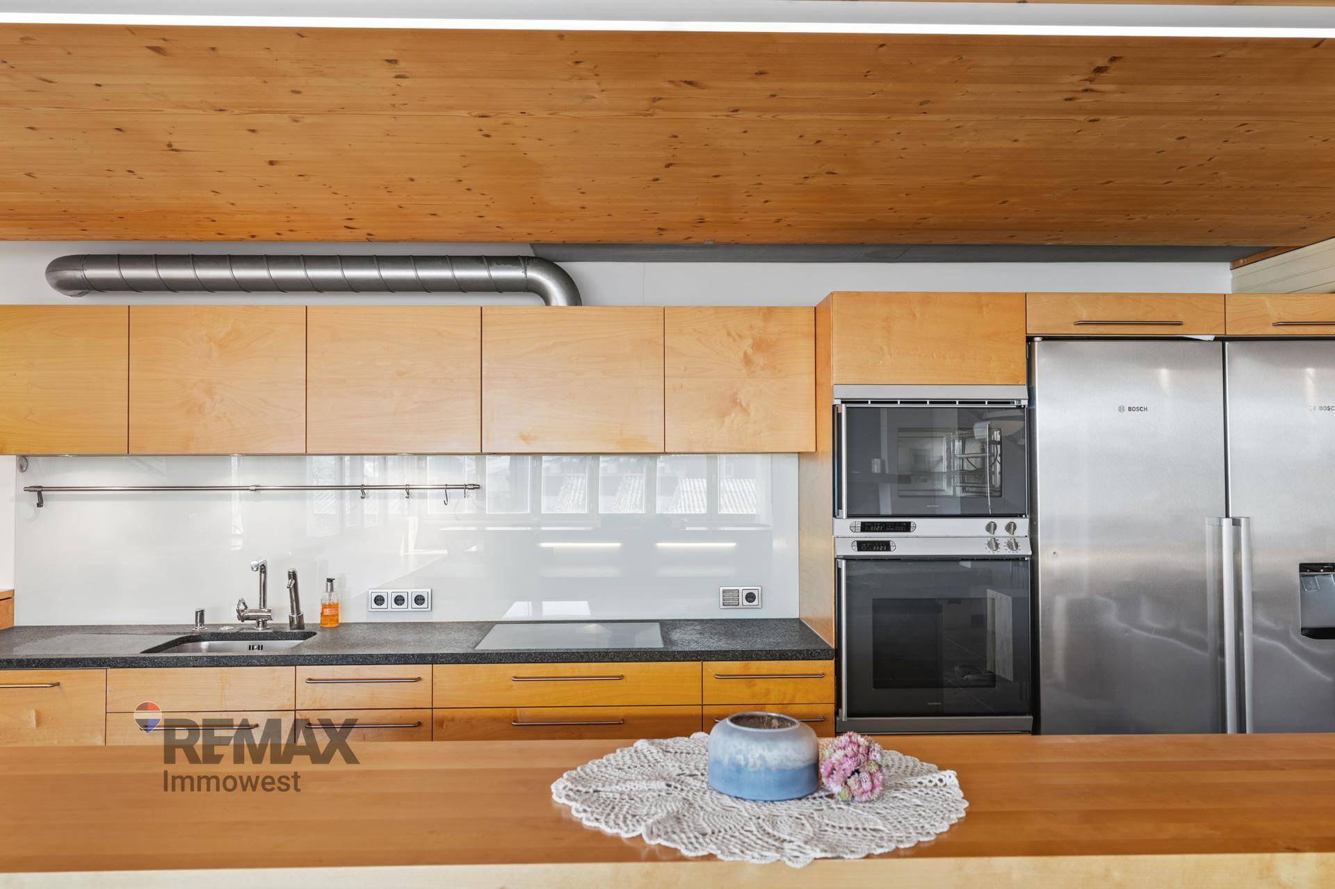 Detailansicht der Küche mit Bosch-Kühlschrank, Backofen und Induktionskochfeld.