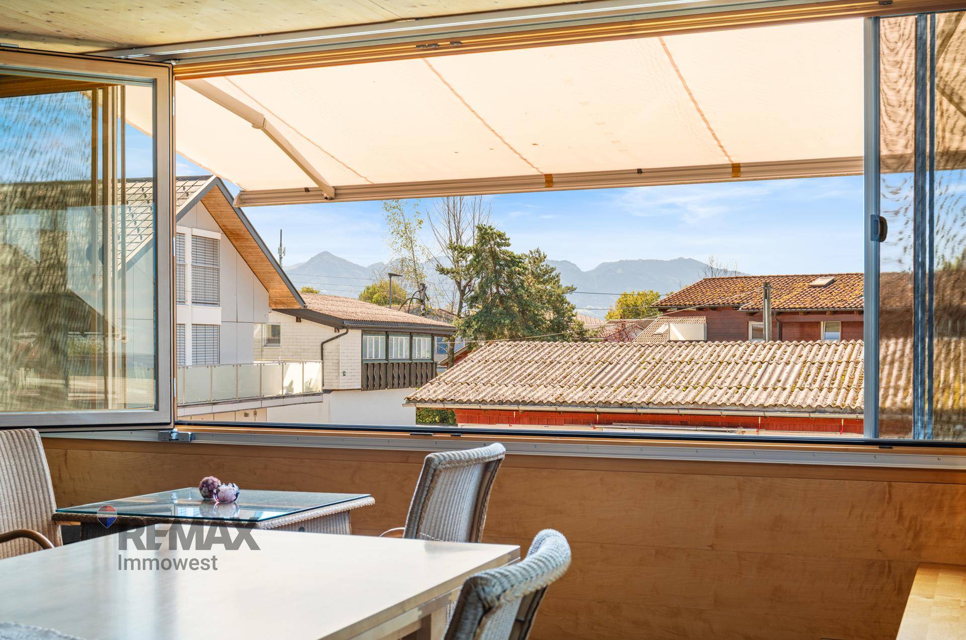 Offener Wintergarten mit ausfahrbarer Markise und Panoramablick auf die Berge.