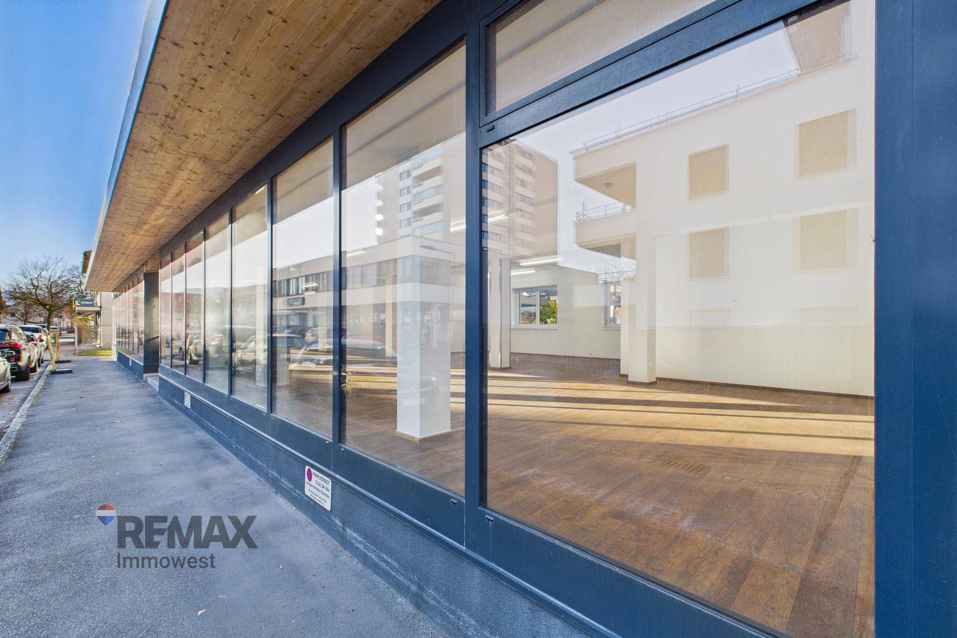 Große Schaufensterfront eines modernen Geschäftsgebäudes mit Holzakzenten und reflektierendem Licht.