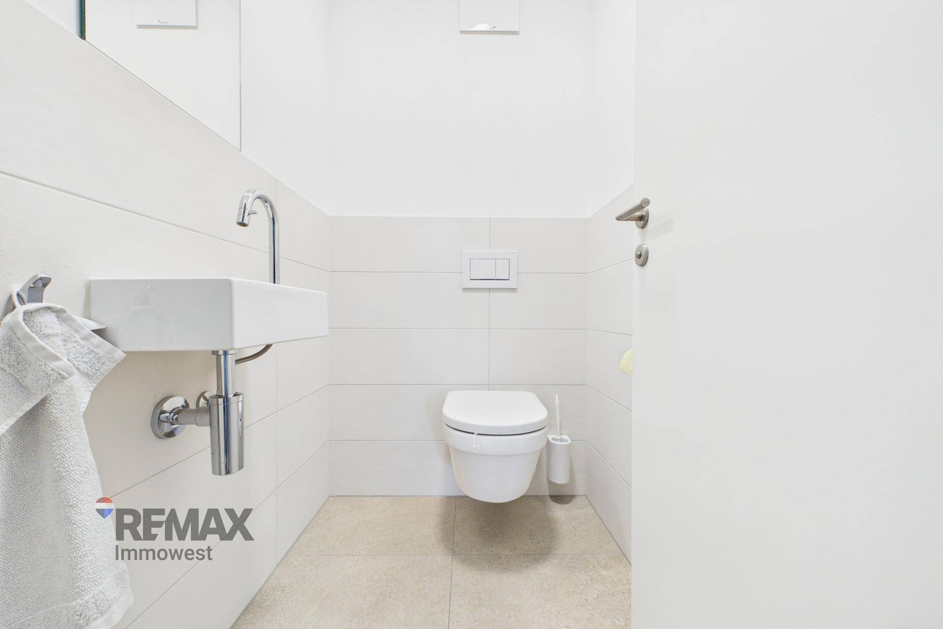 Modernes Gäste-WC mit wandhängender Toilette und kleinem Handwaschbecken.