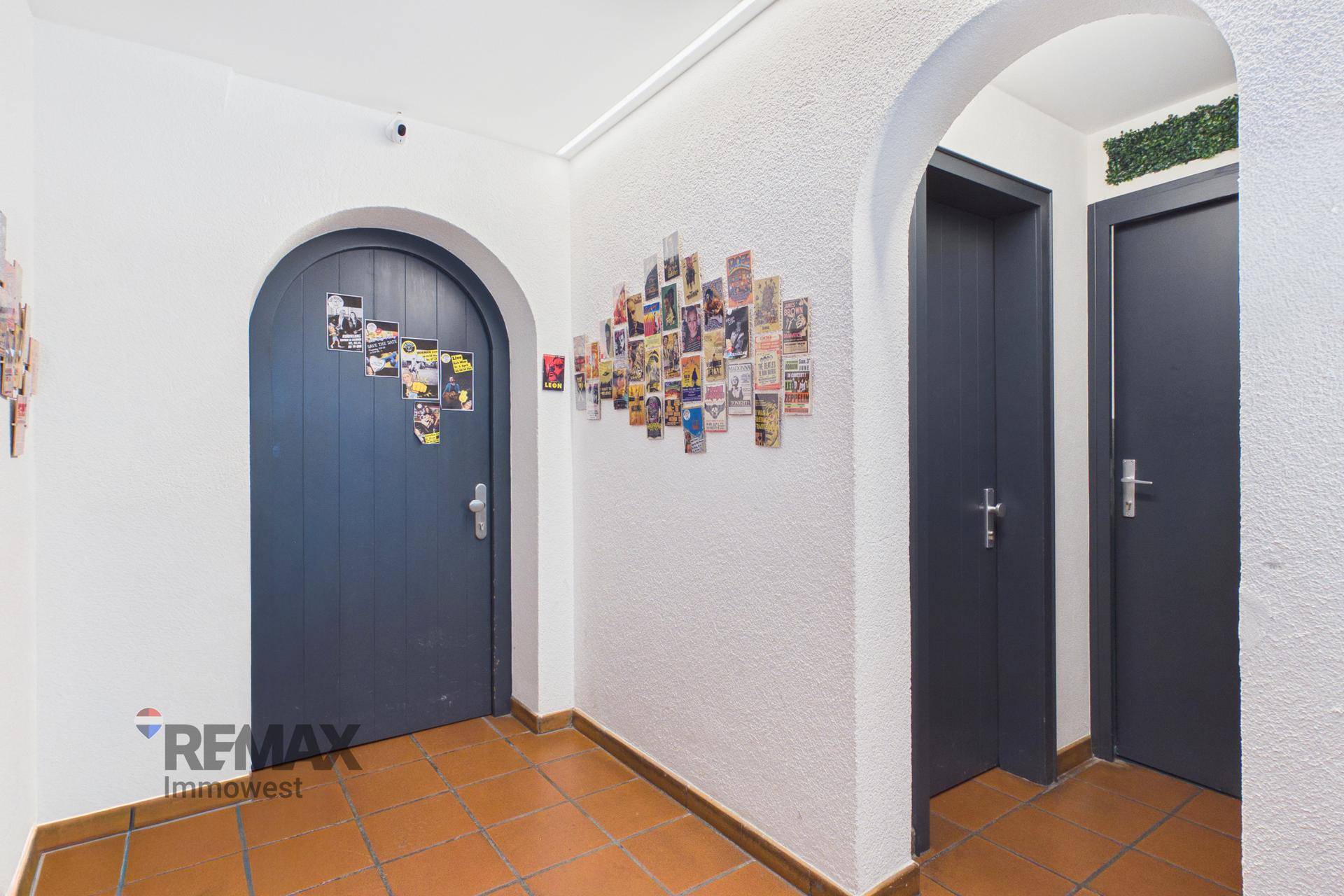 Eingangsbereich mit Terrakottafliesen, gewölbten Türen und einer Wanddekoration aus Postkarten.