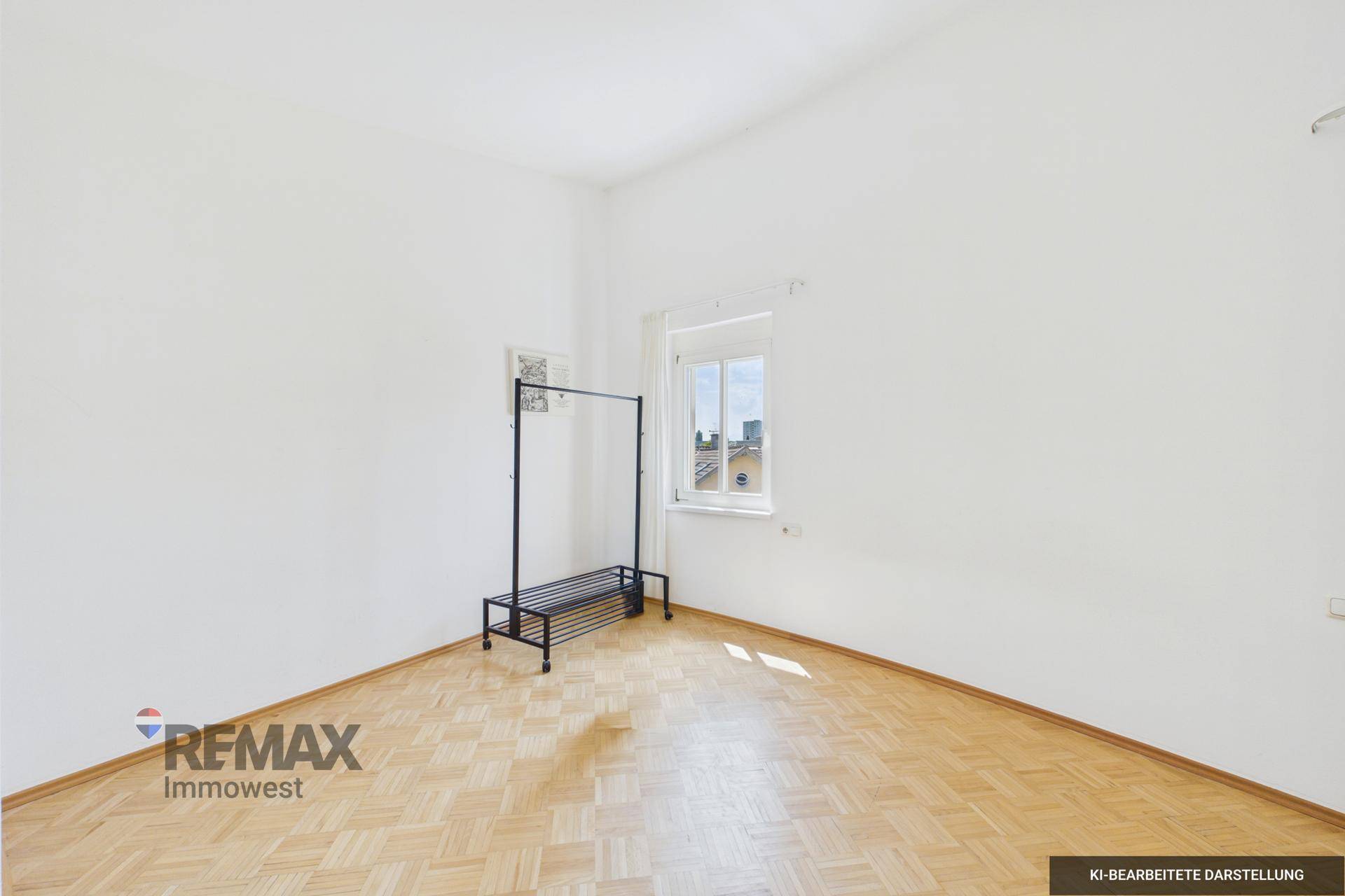 Helles Schlafzimmer mit Parkettboden und einem Fenster mit Blick nach draußen.