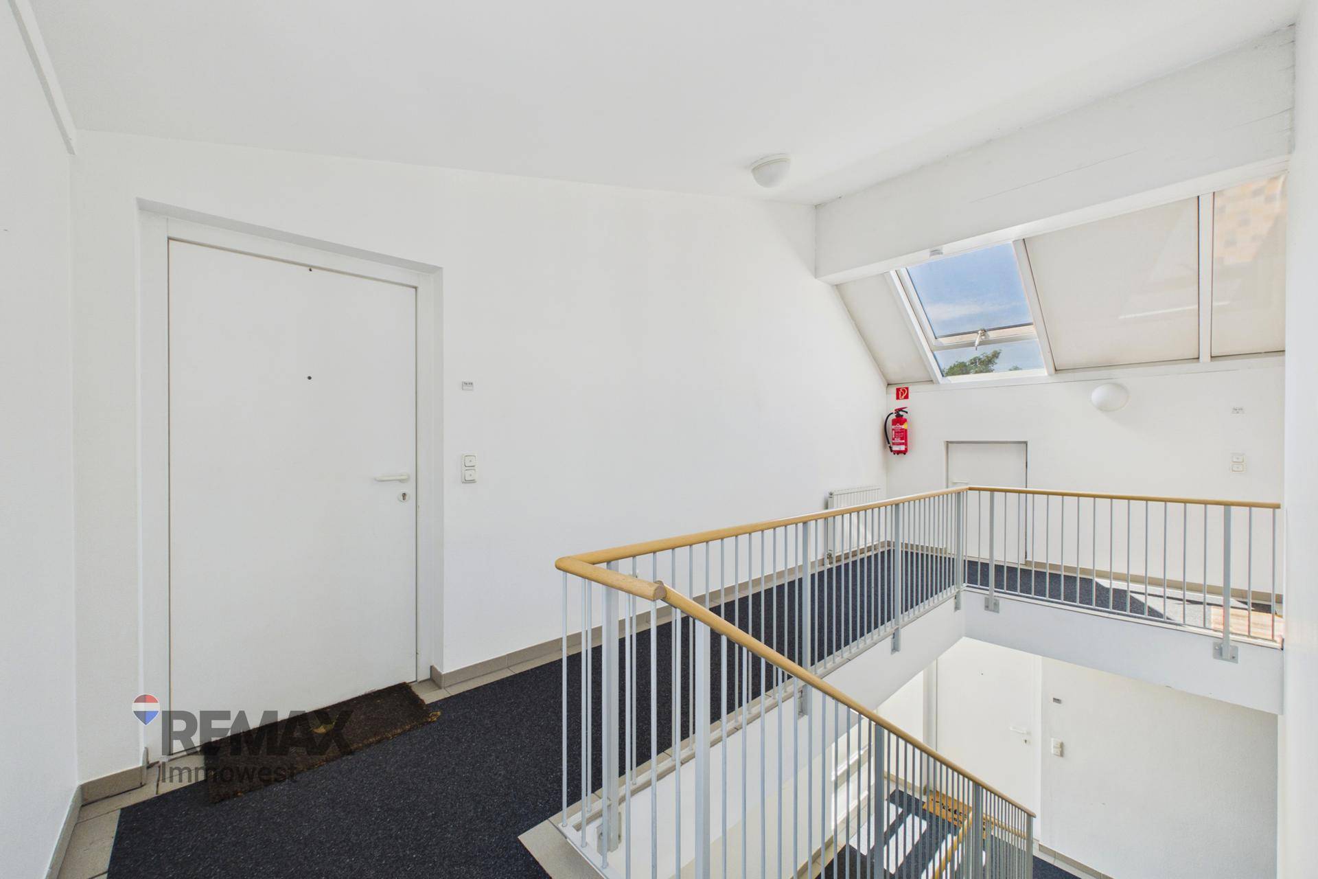 Heller Treppenaufgang mit Holzgeländer und Oberlicht für natürliches Licht.