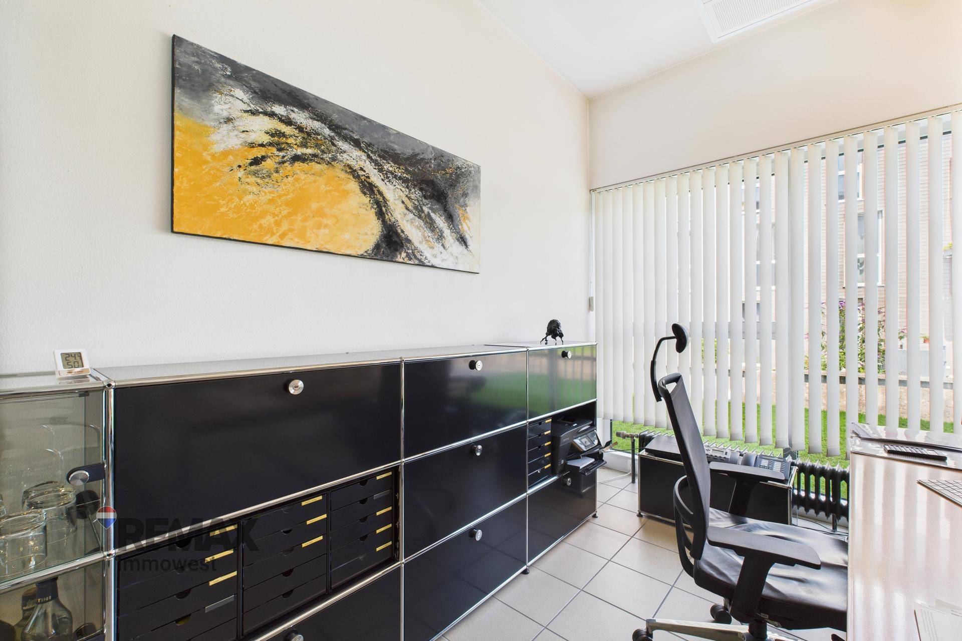 Geräumiges Büro mit umfangreichem schwarzen Schranksystem und einem Arbeitsplatz mit Blick nach draußen.