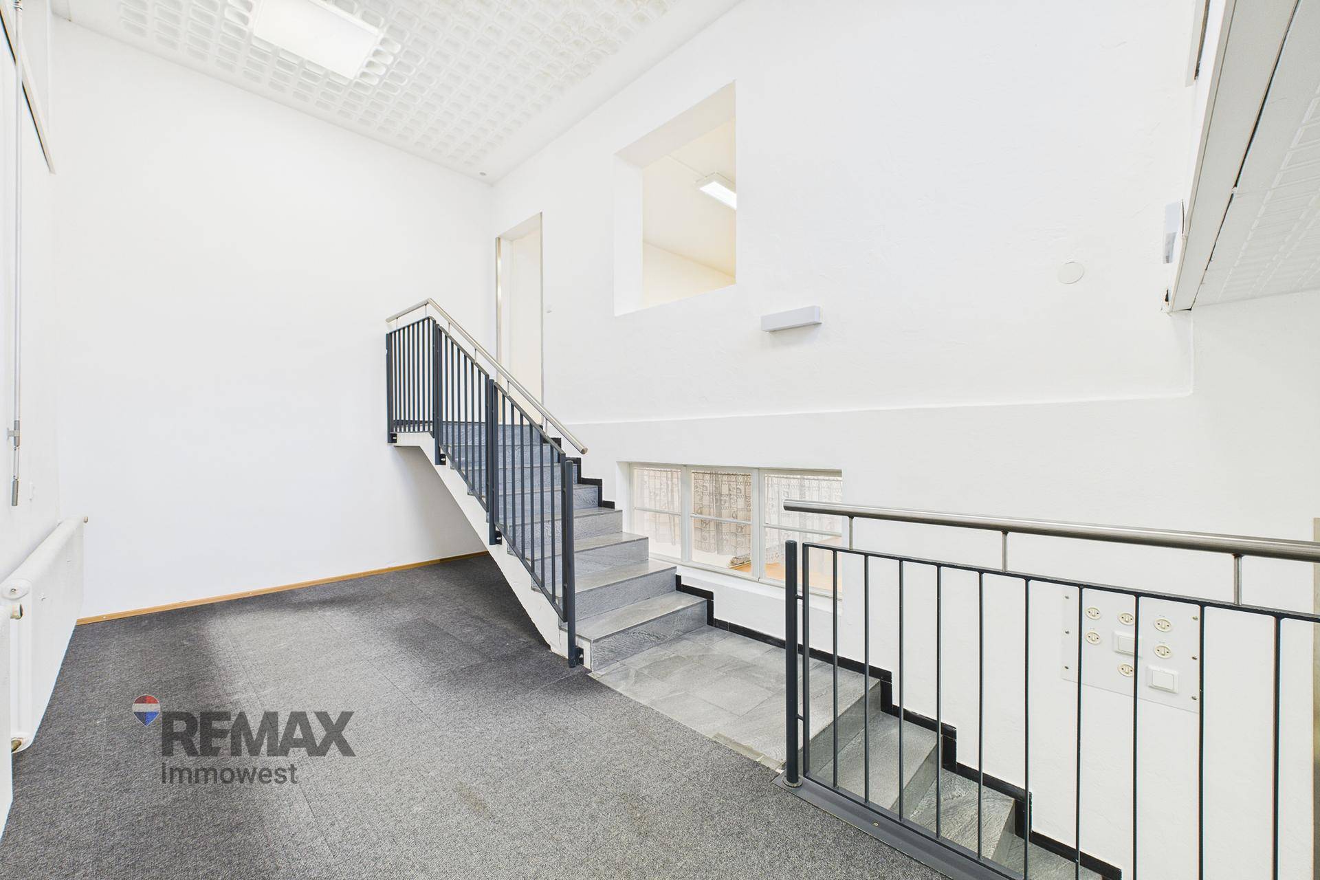 Heller Treppenaufgang mit Metallgeländer und Teppichboden, der zu einer oberen Etage führt.