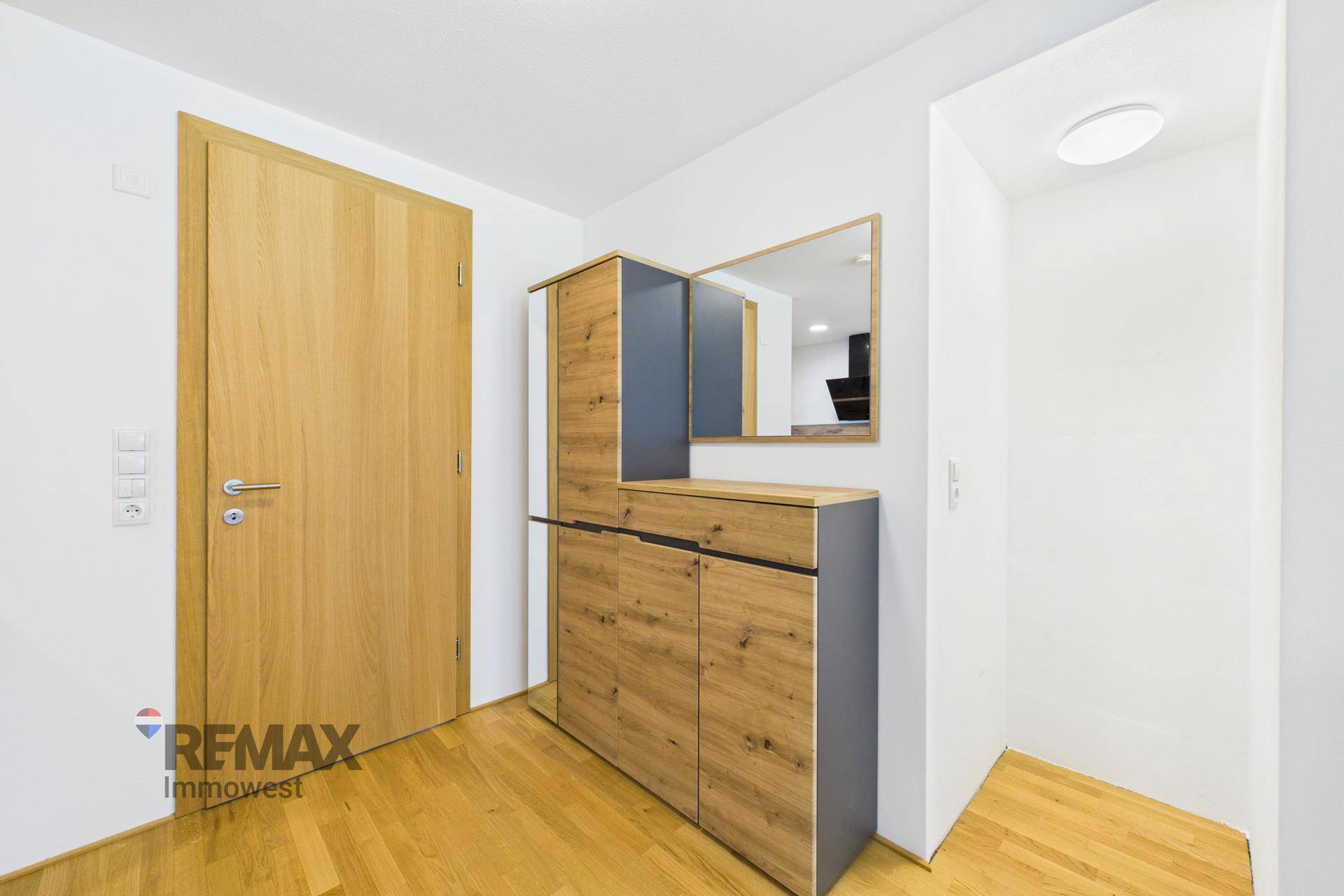 Freundlicher Flur mit Holzparkett, moderner Garderobe und einem Spiegel, der den Raum erweitert.