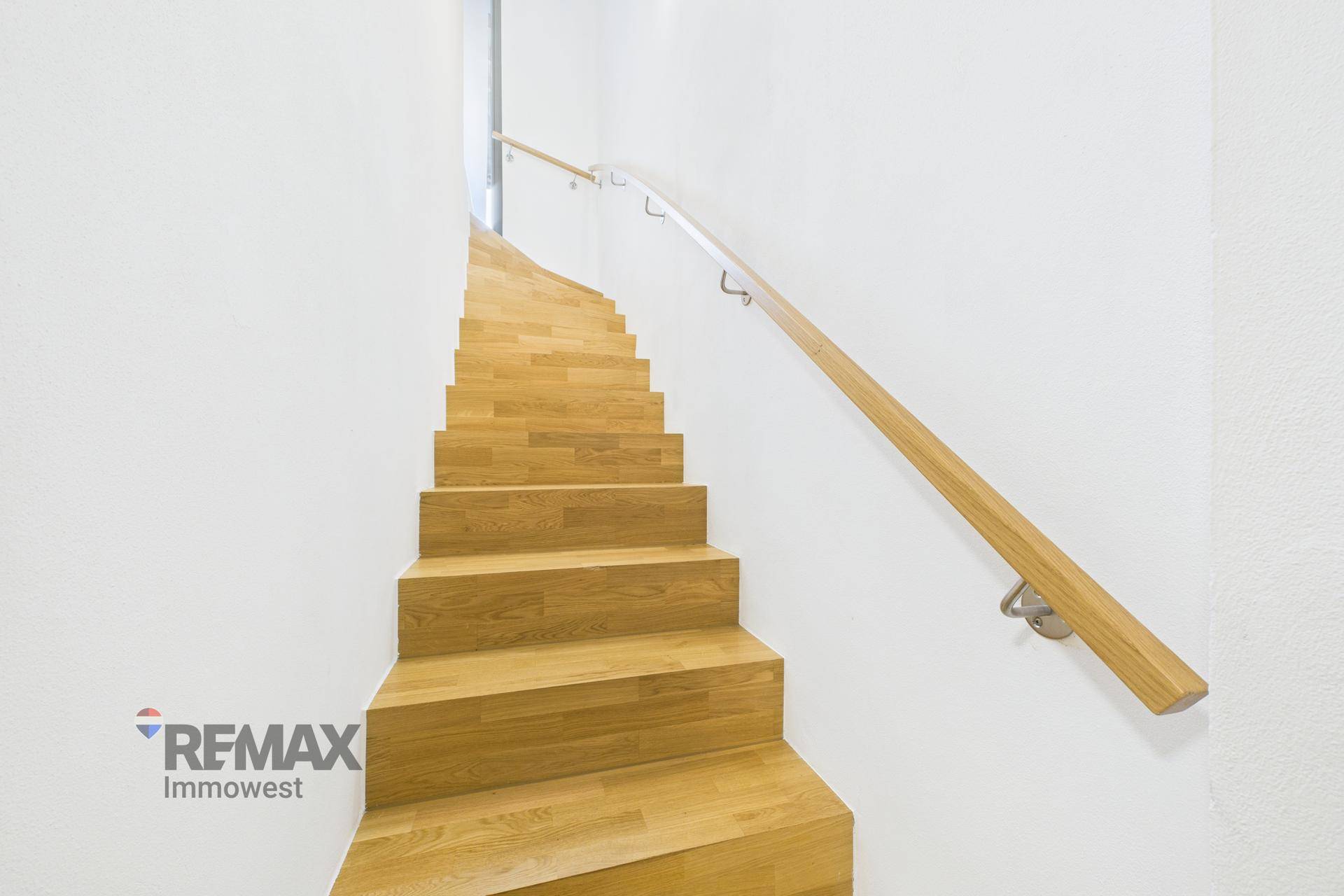 Moderne Holztreppe mit Handlauf, die die verschiedenen Ebenen des Hauses verbindet.