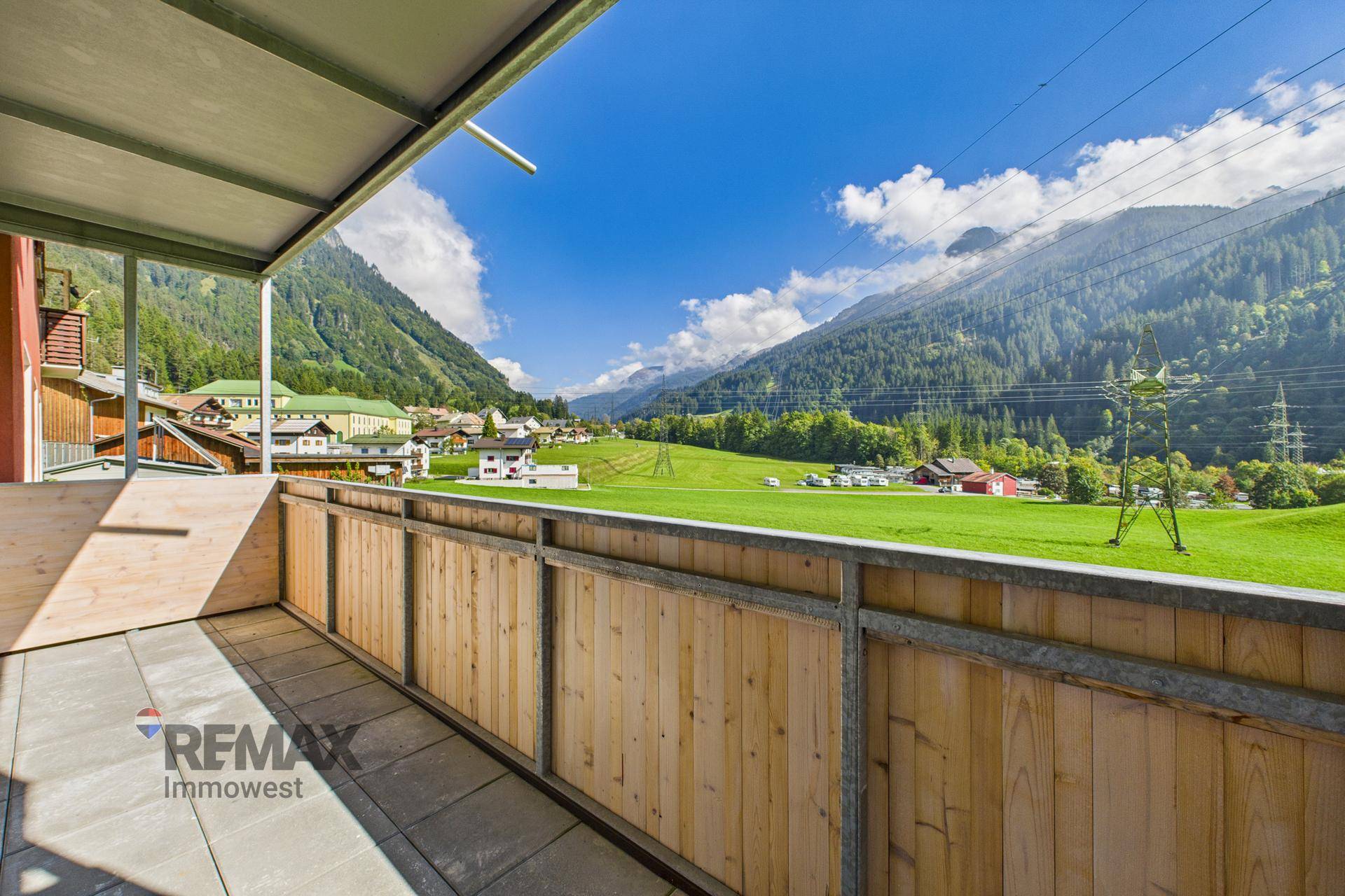 Sonniger Balkon mit Holzboden und atemberaubendem Blick auf die umliegende Berglandschaft.