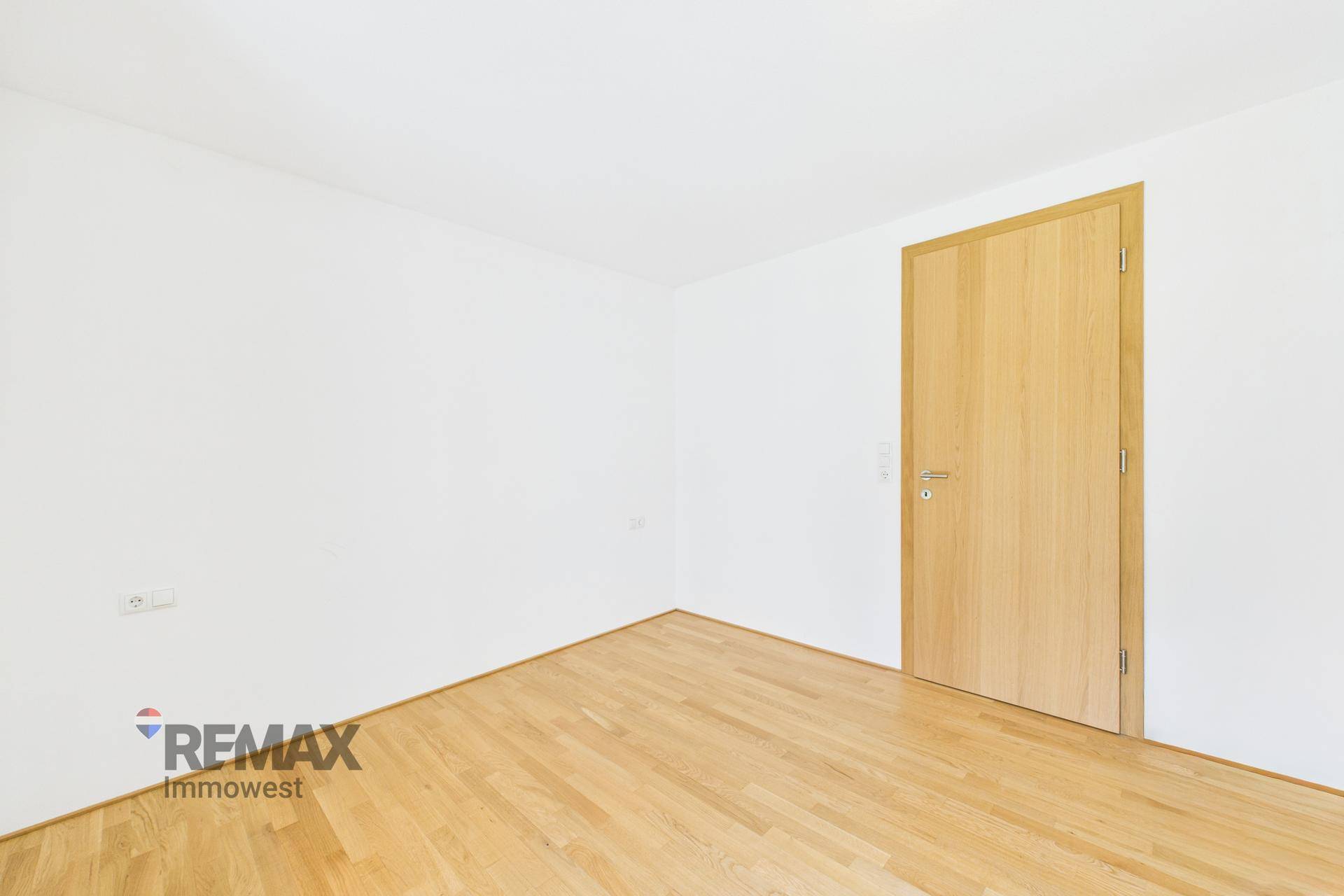 Leeres Zimmer mit Holzboden und einer Holztür, bereit zur individuellen Gestaltung.