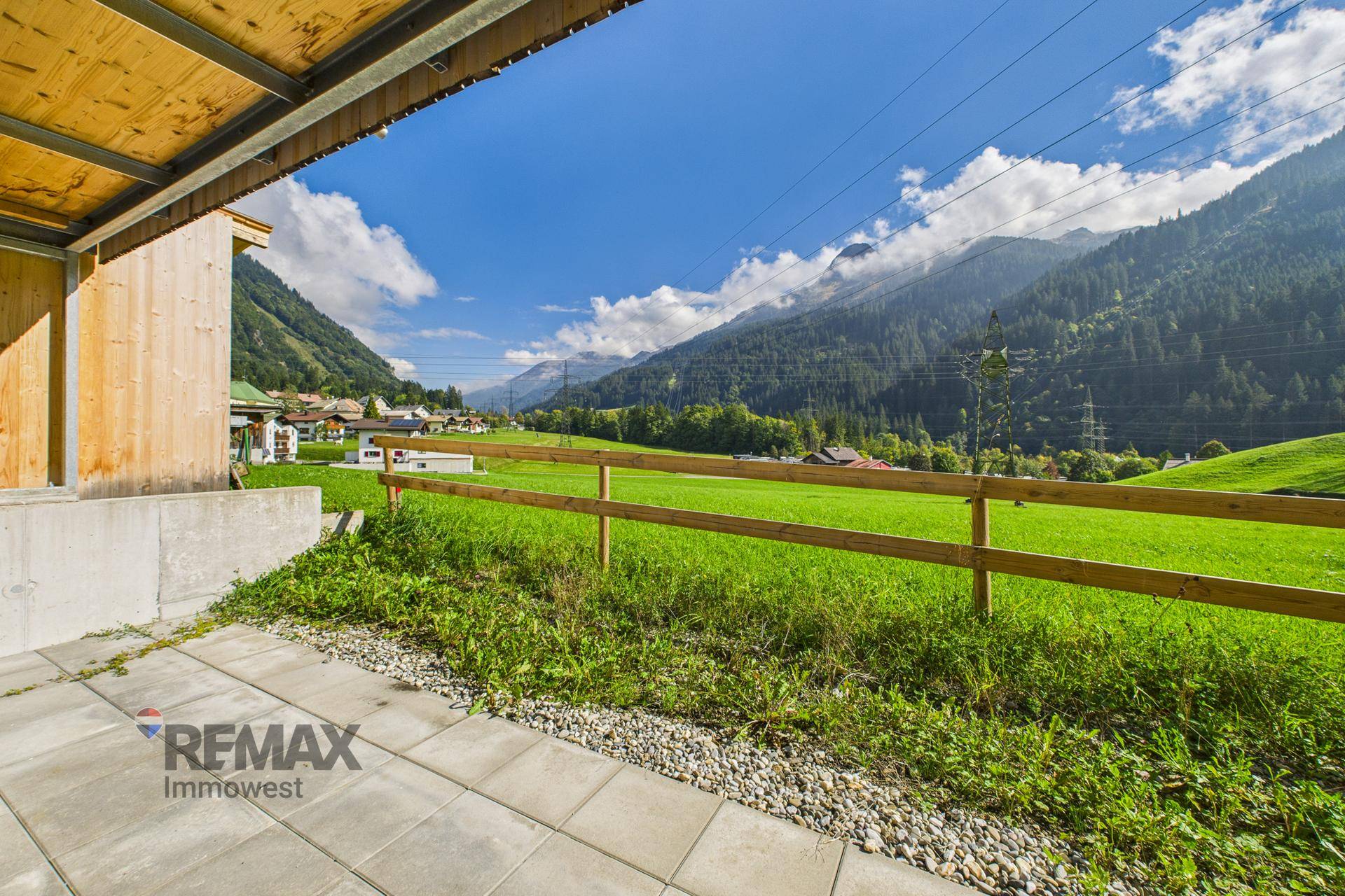 Geräumige Terrasse mit Fliesenboden und weitem Blick über die umliegende Natur und Berge.