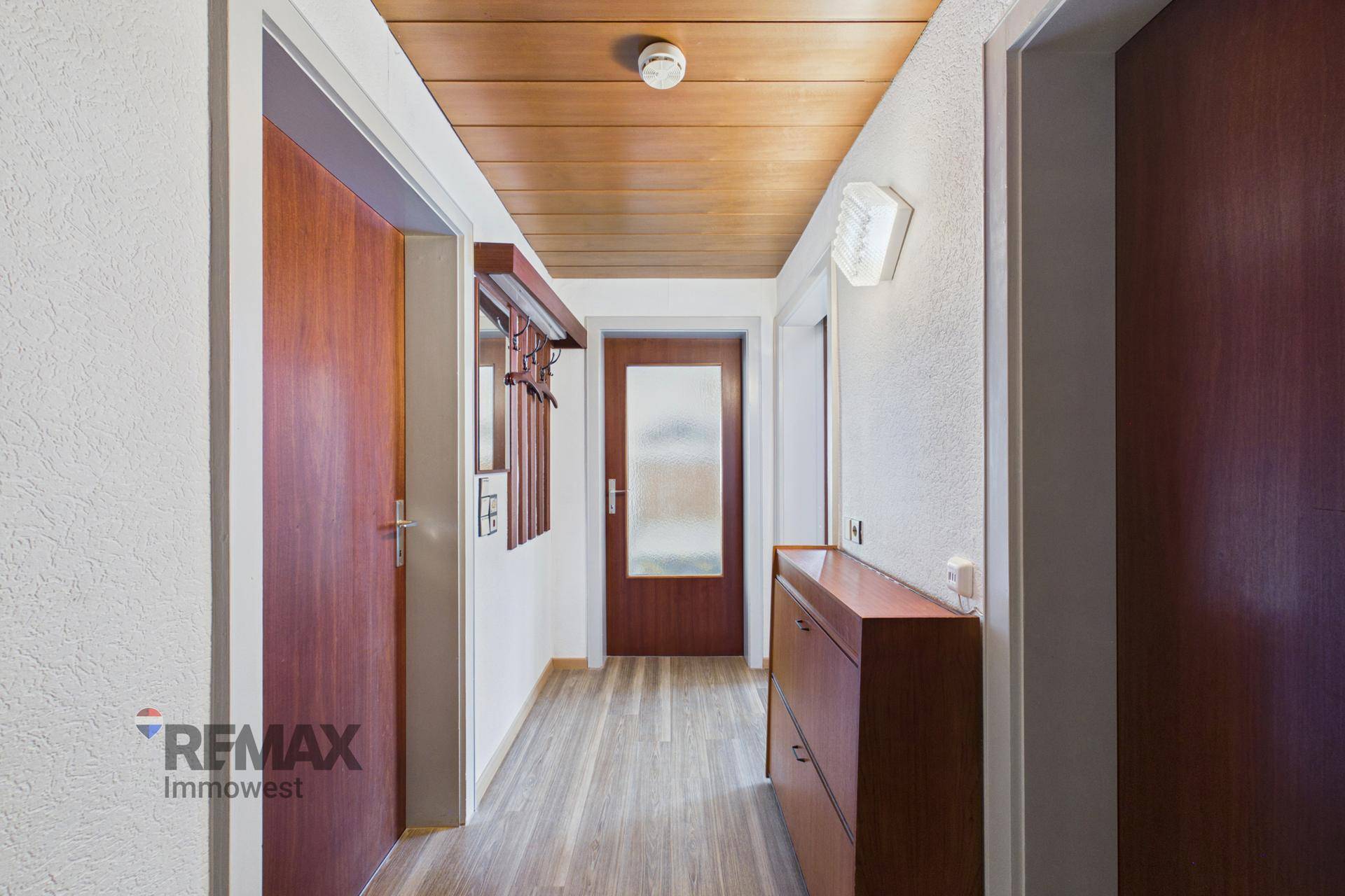 Heller Flur mit Holzdecke und Laminatboden, der zu verschiedenen Räumen führt und gut gepflegt ist.