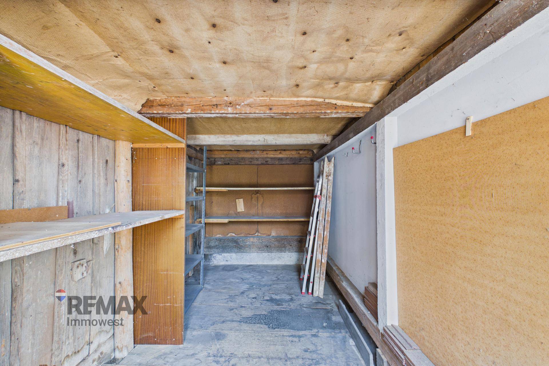 Geräumiger Lagerraum mit Holzverkleidung, Regalen und Betonboden, bietet vielseitige Nutzungsmöglichkeiten.