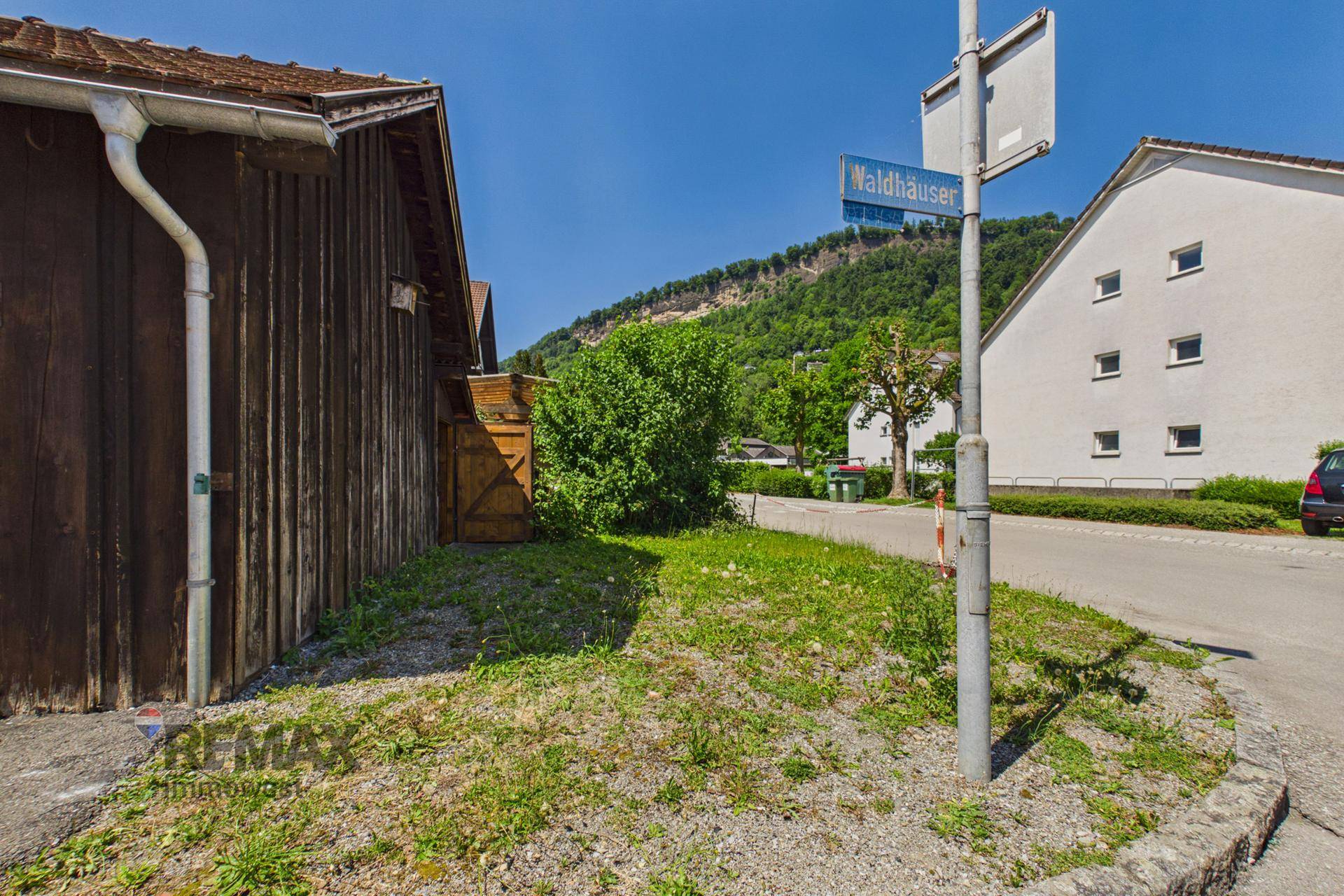 Ländliche Straße mit Grünflächen und Blick auf die umliegenden Berge, bietet eine ruhige Umgebung.