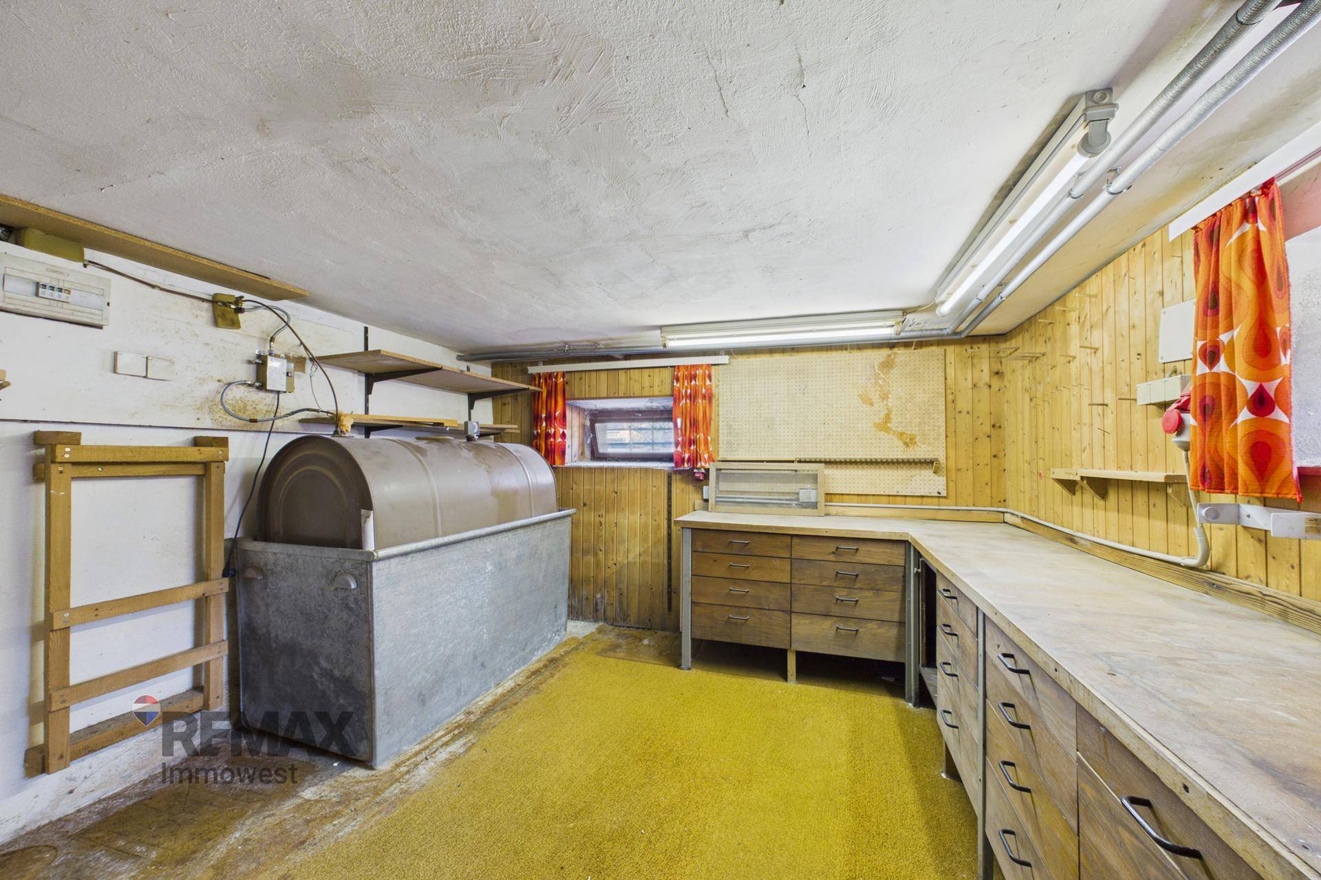 Kellerraum mit Werkbank, Lagerbehälter und Holzverkleidung an den Wänden, ideal für Hobby und Lagerung.