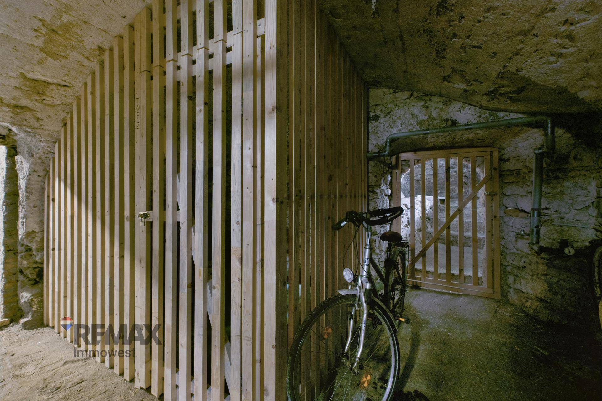 Kellerraum mit Holzabtrennungen und Abstellmöglichkeiten, inklusive Fahrrad.